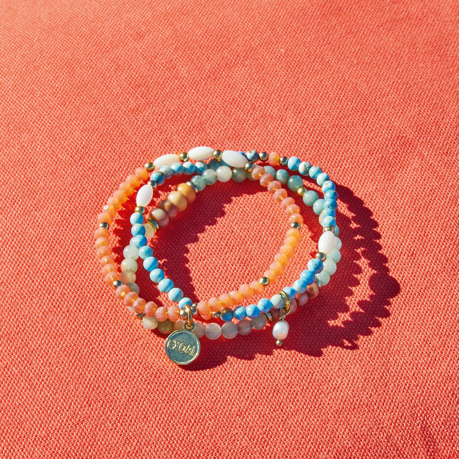 Bunte Perlenarmband mit Anhänger auf orangefarbenem Hintergrund, modischer Damenschmuck