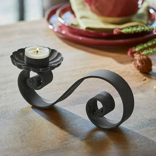 Schwarzer Metall-Kerzenhalter mit geschwungenem Design für Teelicht auf Holztisch