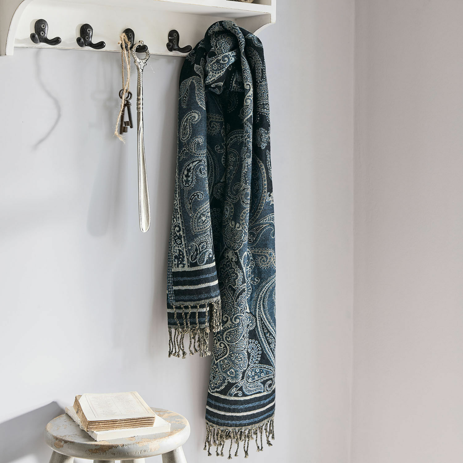 Schal Eloas Dunkelblauer Schal mit Paisley-Muster und Fransen an weißem Haken in hellem Raum