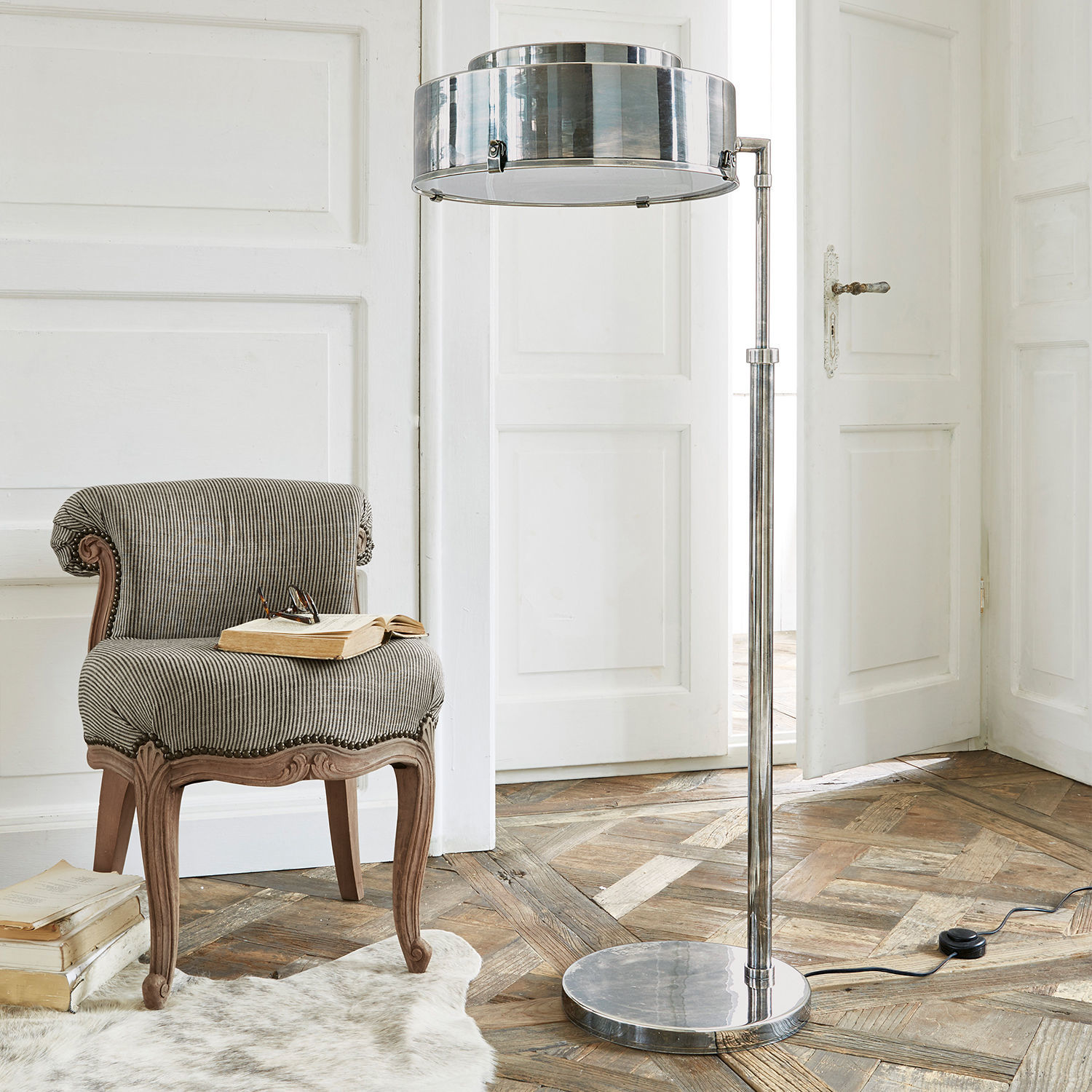 Stehlampe aus Edelstahl im modernen Design auf Holzboden mit weißem Teppich