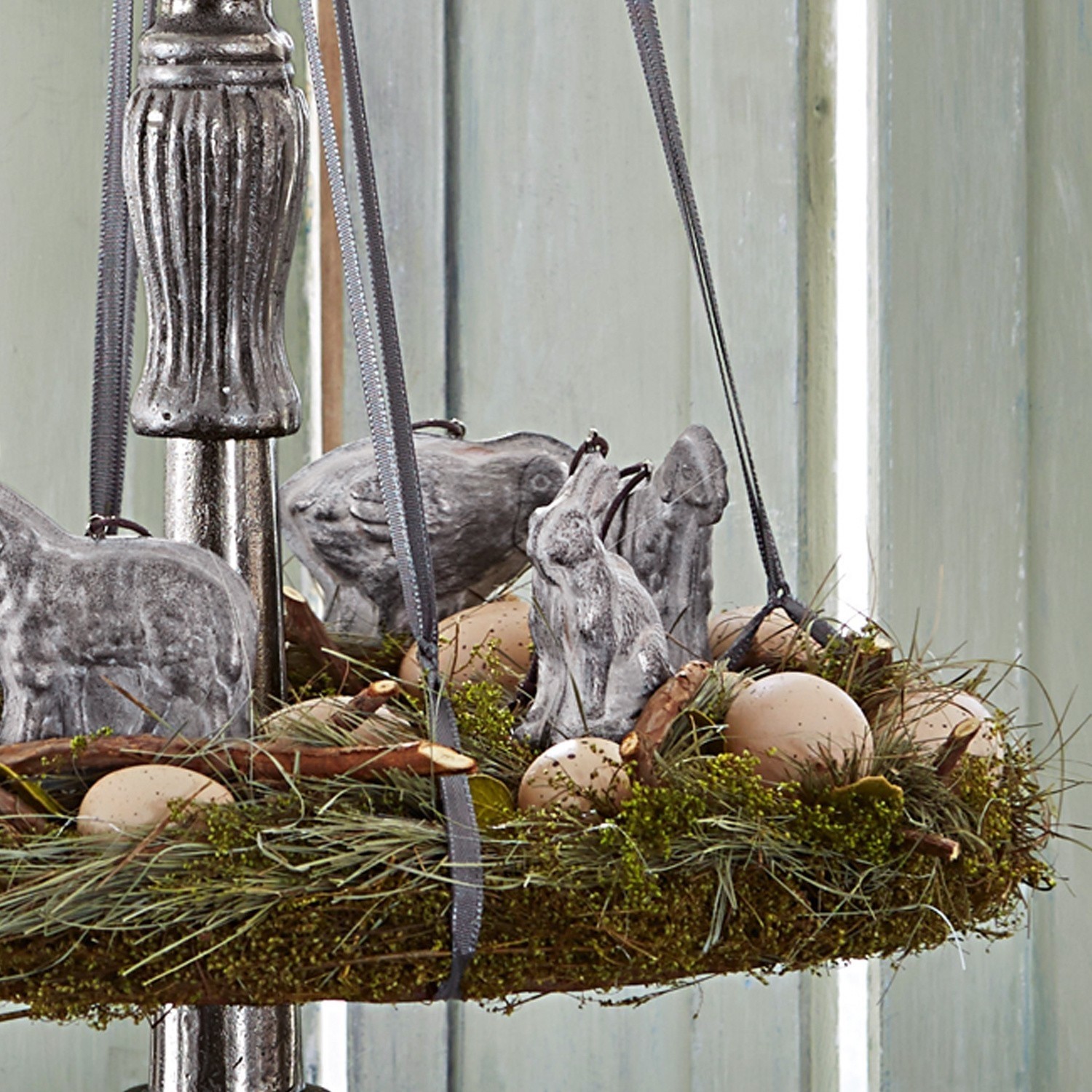 Dekorativer Kranz aus Gras und Moos mit grauen Tierfiguren und beigen Eiern für den Frühling