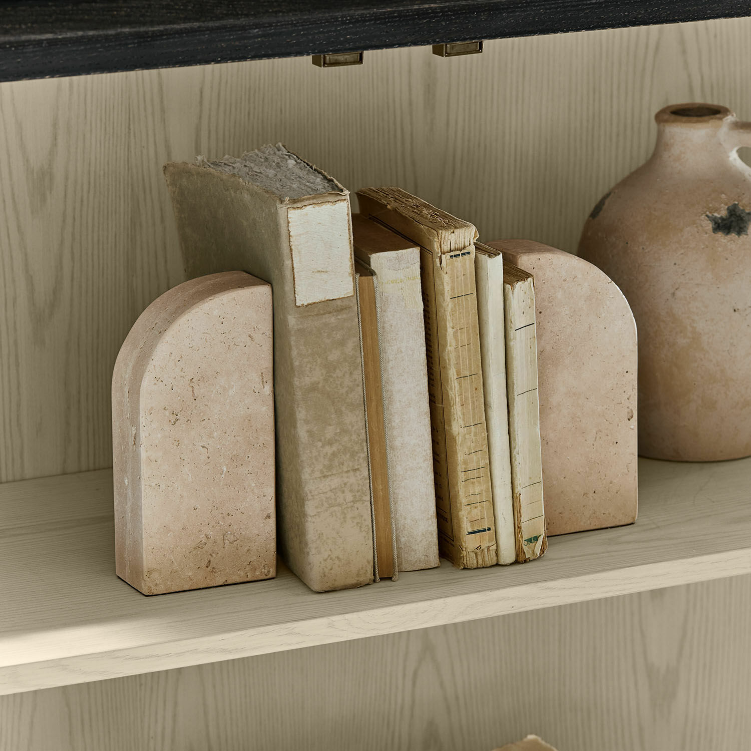 Paar beige Steingestützte Buchstützen auf Holzregal mit alten Büchern