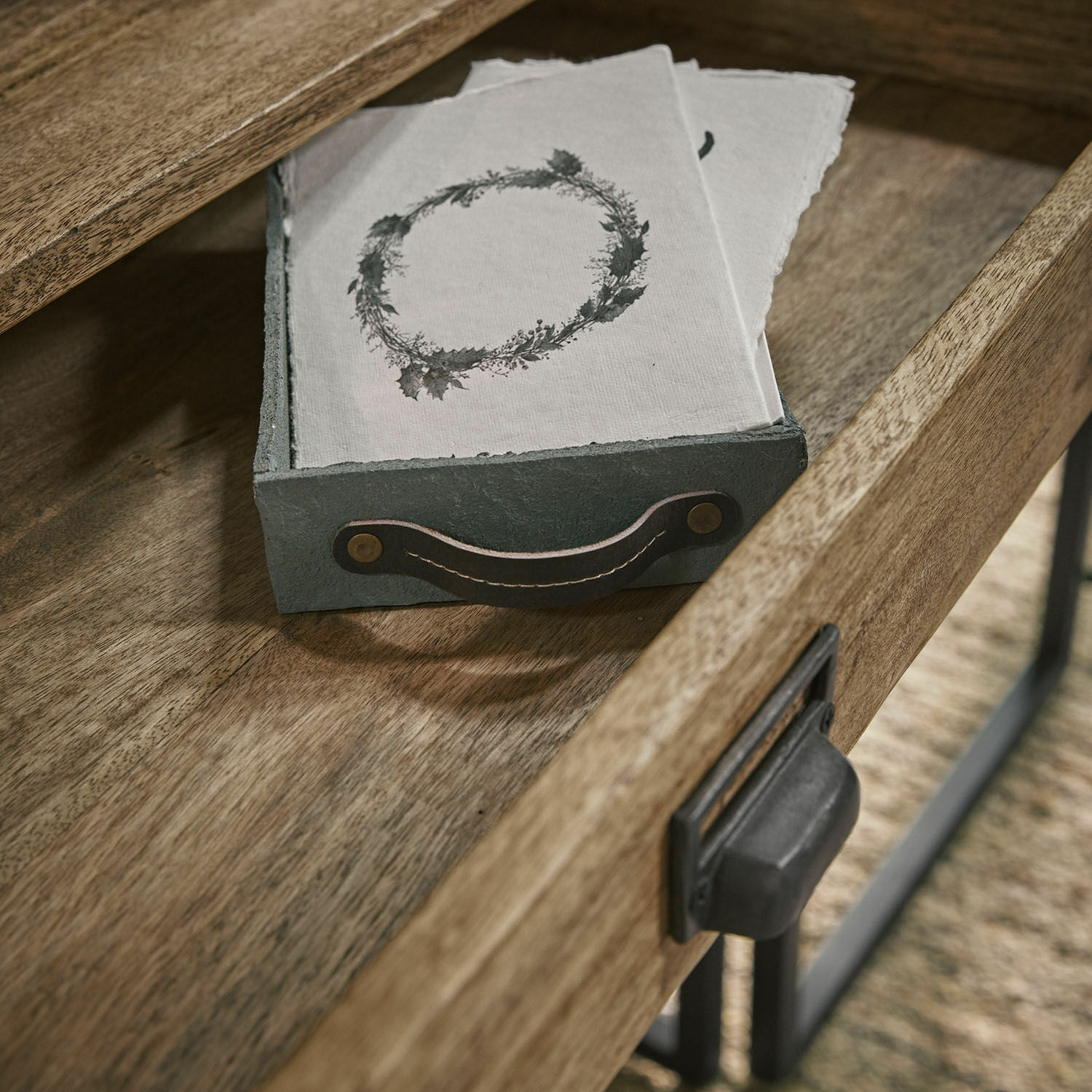 Graue Stofftasse mit schwarzem Griff auf Holztisch mit Servietten und Kranzmotiv