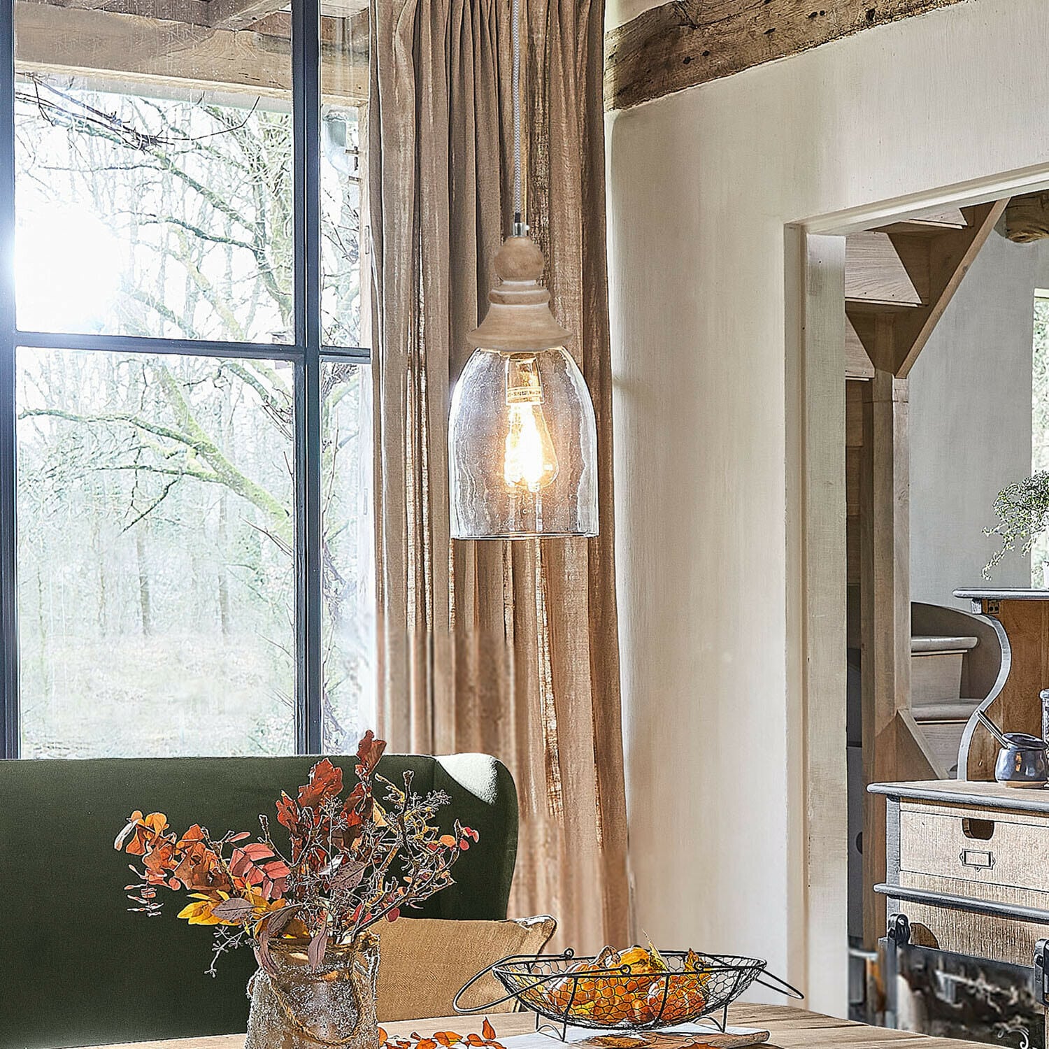 Rustikaler Holztisch mit herbstlicher Dekoration und hängender Lampe in gemütlichem Wohnzimmer