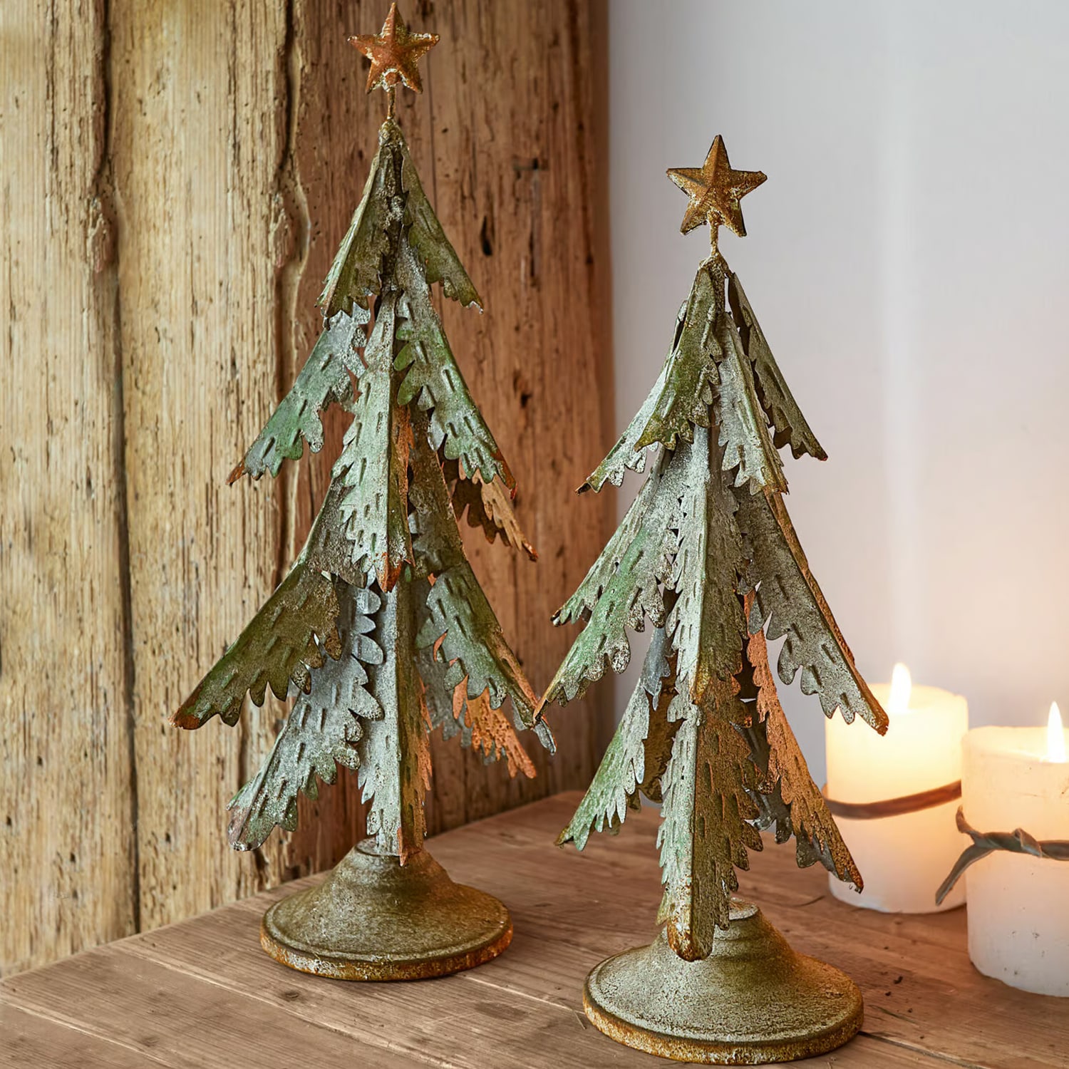 Zwei grüne Metall-Weihnachtsbäume mit goldenen Sternen als rustikale Tischdekoration