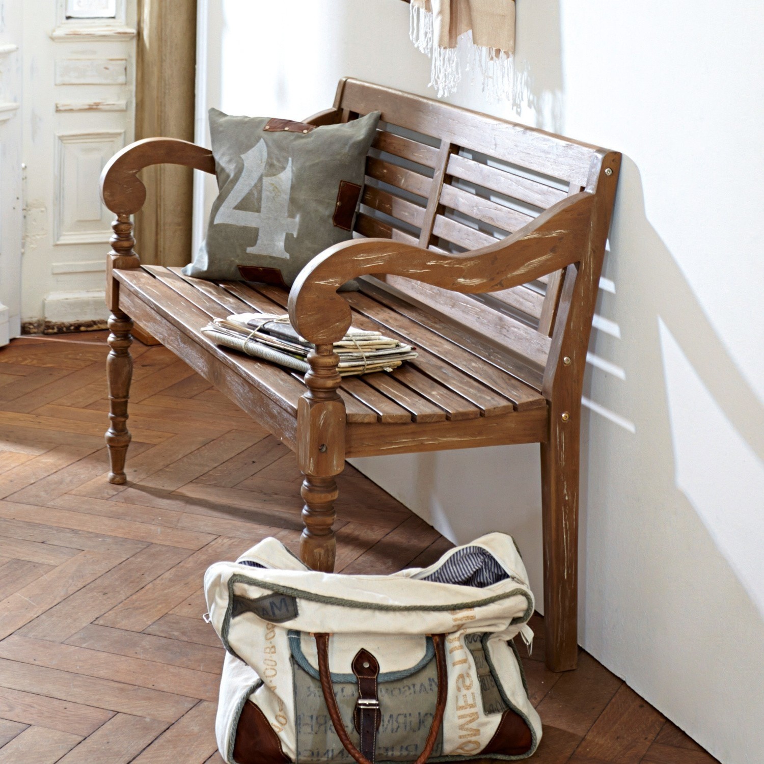 Vintage Holzbank mit Armlehnen, Kissen und Tasche auf Parkettboden in hellem Raum