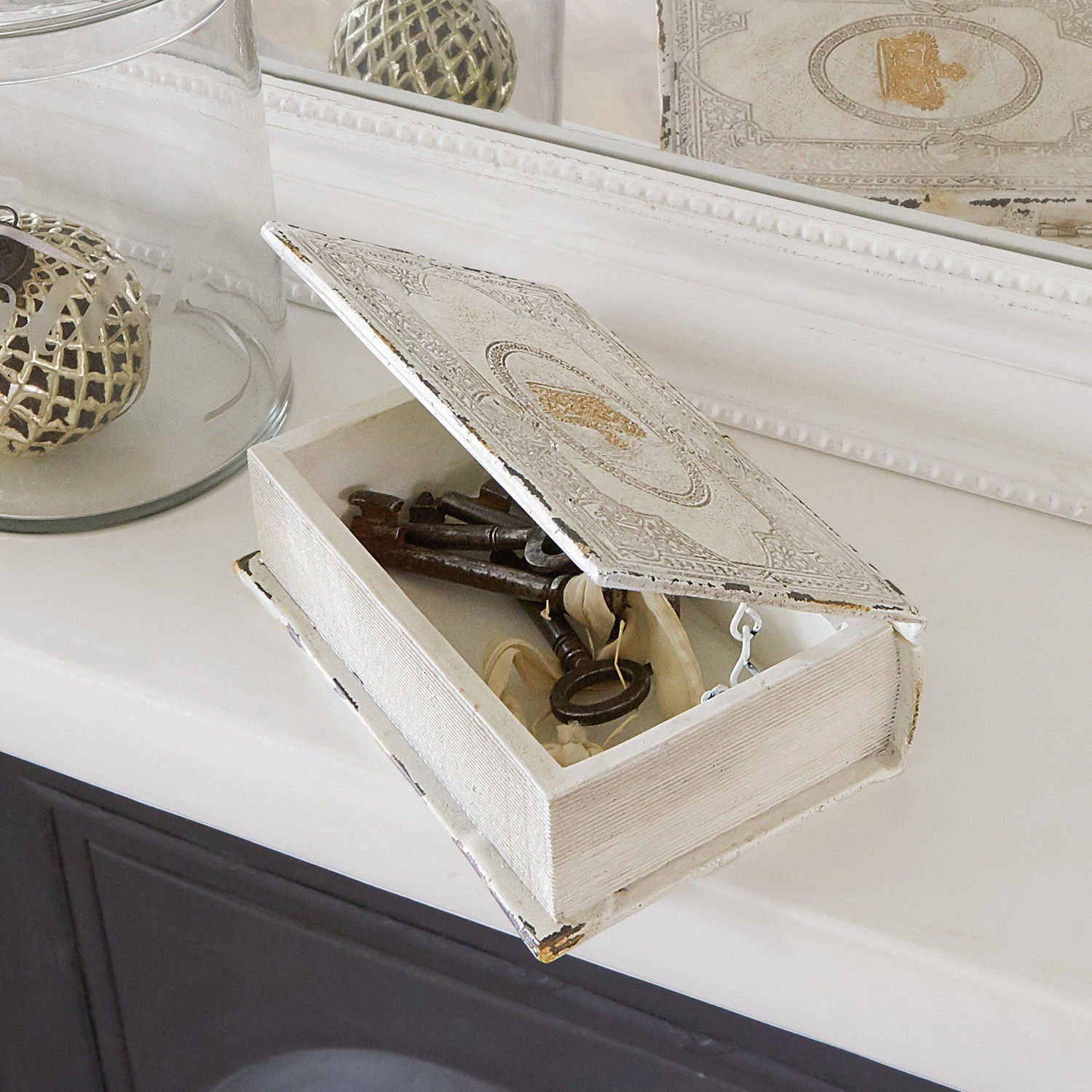 Weiße Holzbox in Buchform mit Metallschlüsseln auf Ablage, Vintage-Dekoration