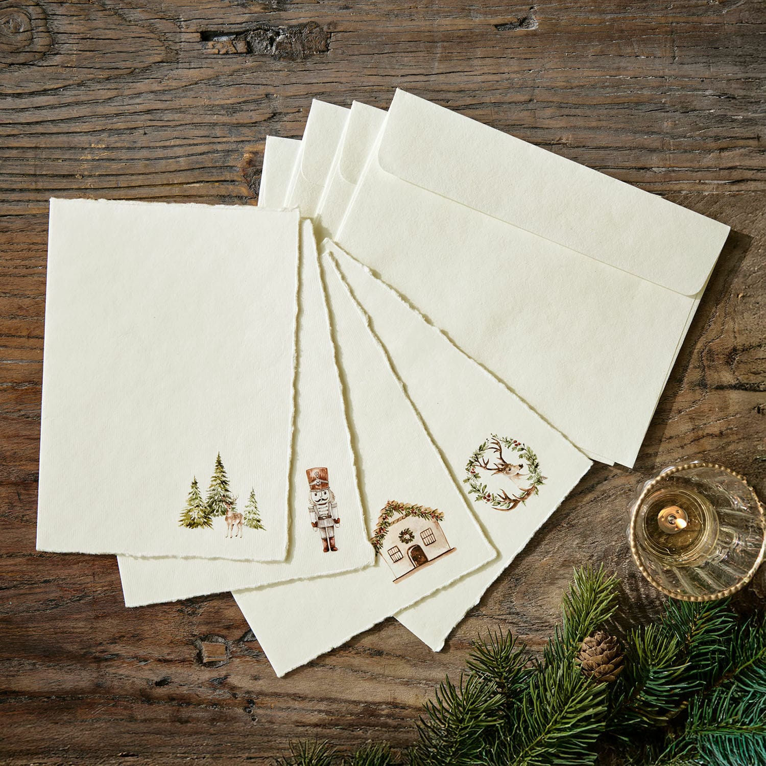 Grußkarte 4er Set Lorandis Set aus cremefarbenen Briefkarten und Umschlägen mit Weihnachtsmotiven auf Holztisch mit Tannenzweigen