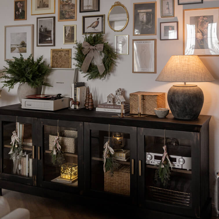 Schwarzer Holz-Sideboard mit Glastüren, weihnachtlicher Dekoration und Keramiklampe im Wohnzimmer
