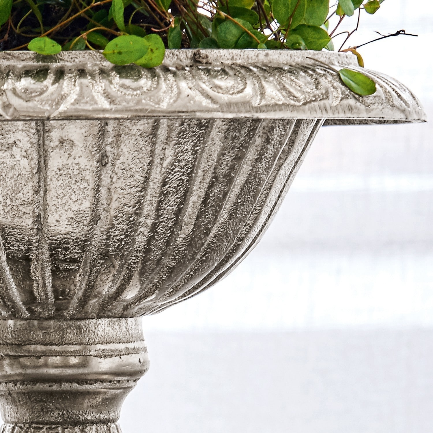 Dekorativer Pflanztopf aus grauem Stein mit grünen Blättern, Garten- und Wohnaccessoire