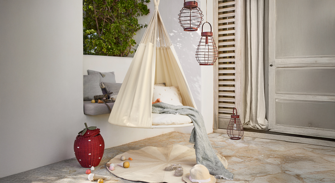 Beige hängende Stoffschaukel mit Kissen und grauer Decke auf Terrasse, gemütliche Gartendeko