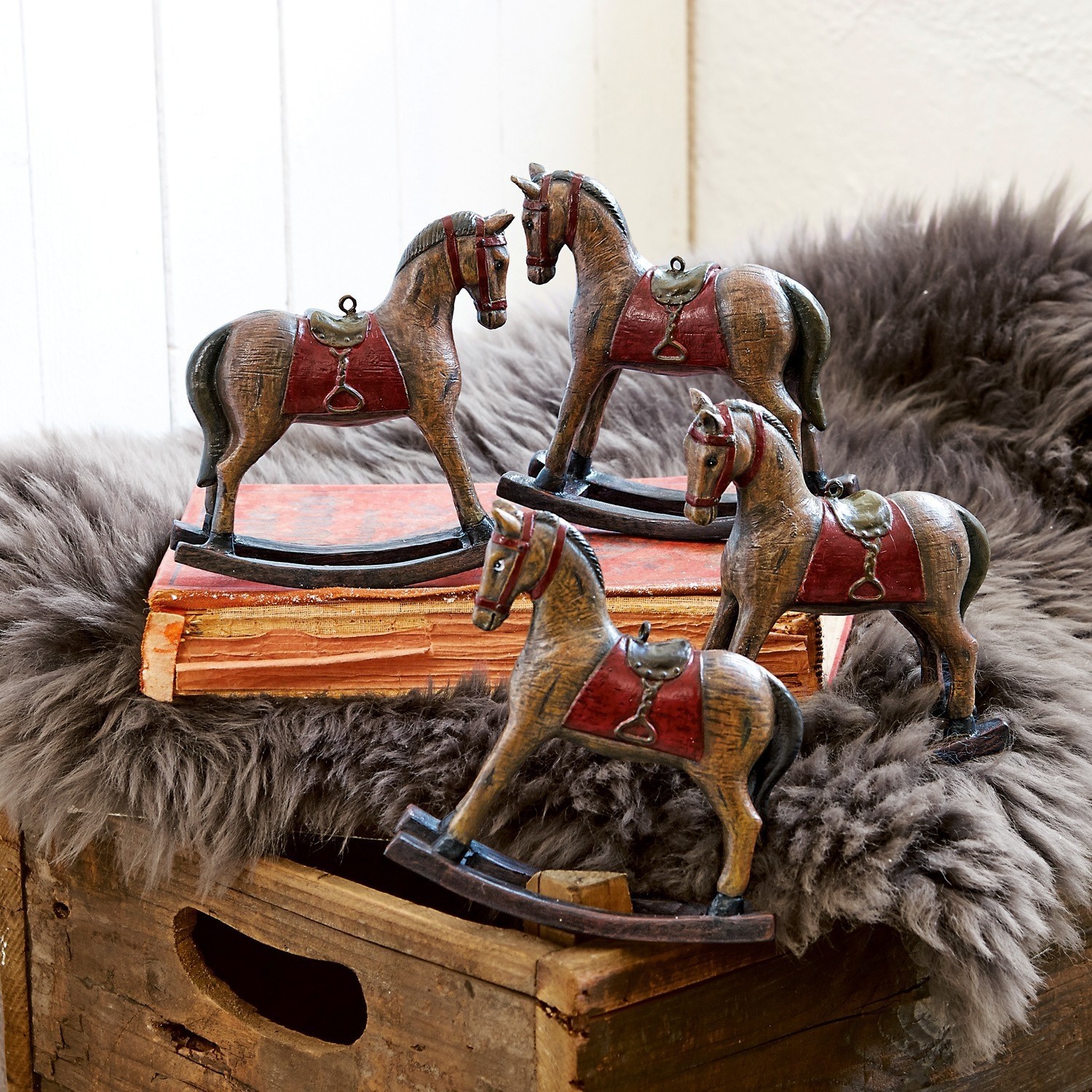 Deko-Pferde 4er Set Cory Vier braune Holz-Schaukelpferde mit roten Sätteln als rustikale Wohnaccessoires.