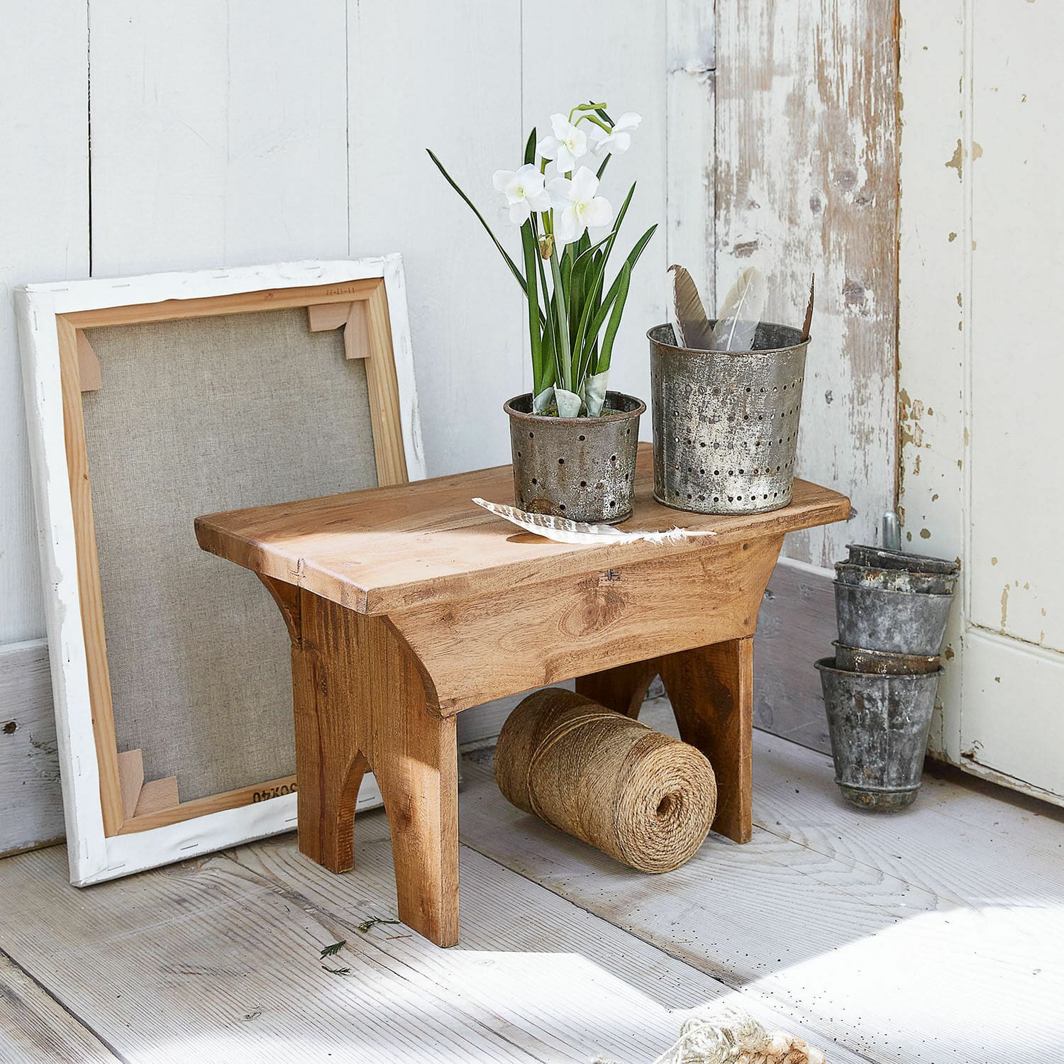 Hocker Hoboken Kleiner Holzschemel mit Metalltöpfen und weißen Blumen auf hellem Holzboden