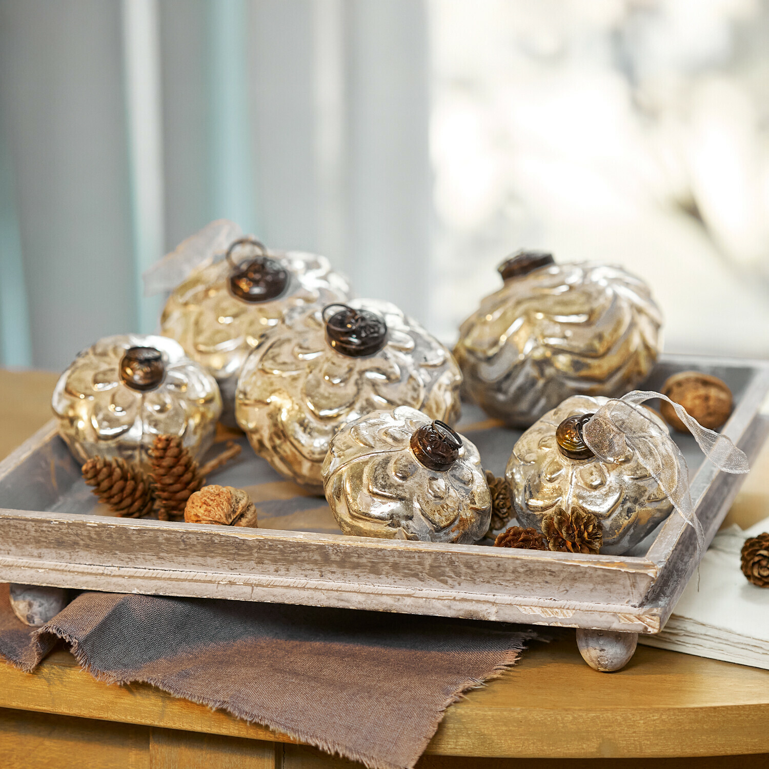 Weihnachtskugel 6er Set Xilianne Dekorative silberne Glasornamente in Blumenform auf einem Holztablett auf dem Tisch