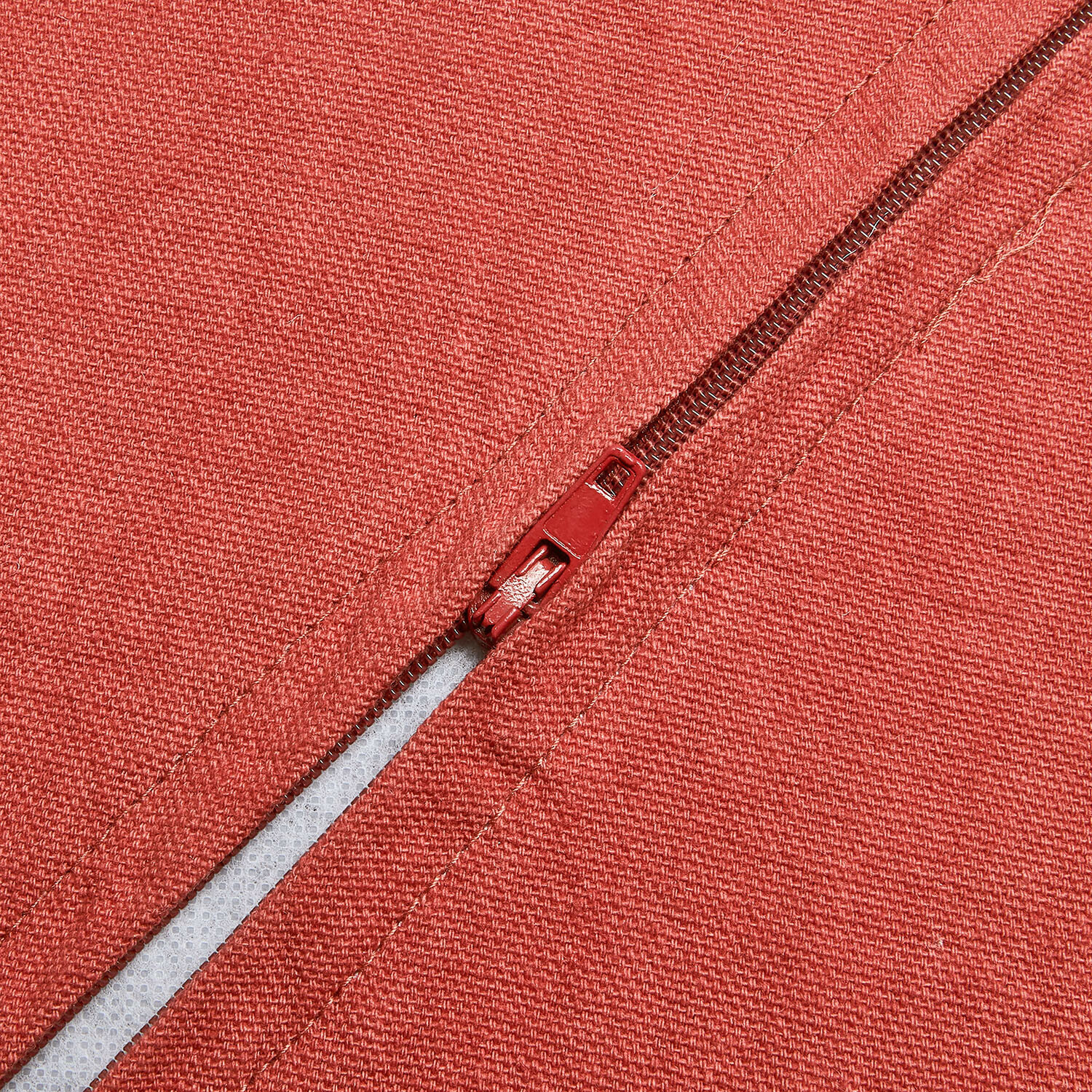 Roter Reißverschluss auf strukturiertem rotem Stoff, Detail eines dekorativen Textils