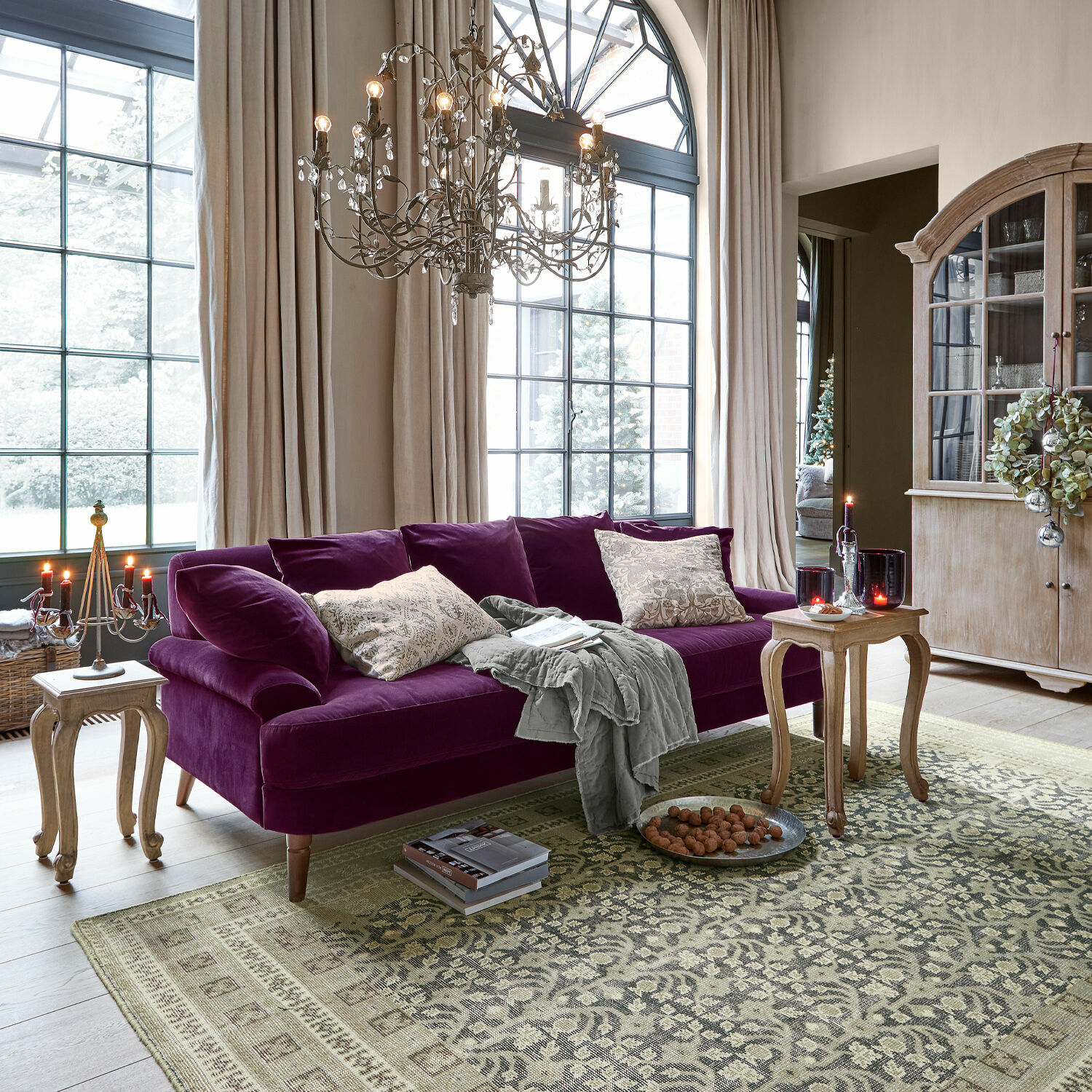 Violettes Samtsofa im Wohnzimmer mit Holztischen und großen Fenstern, Vintage-Stil