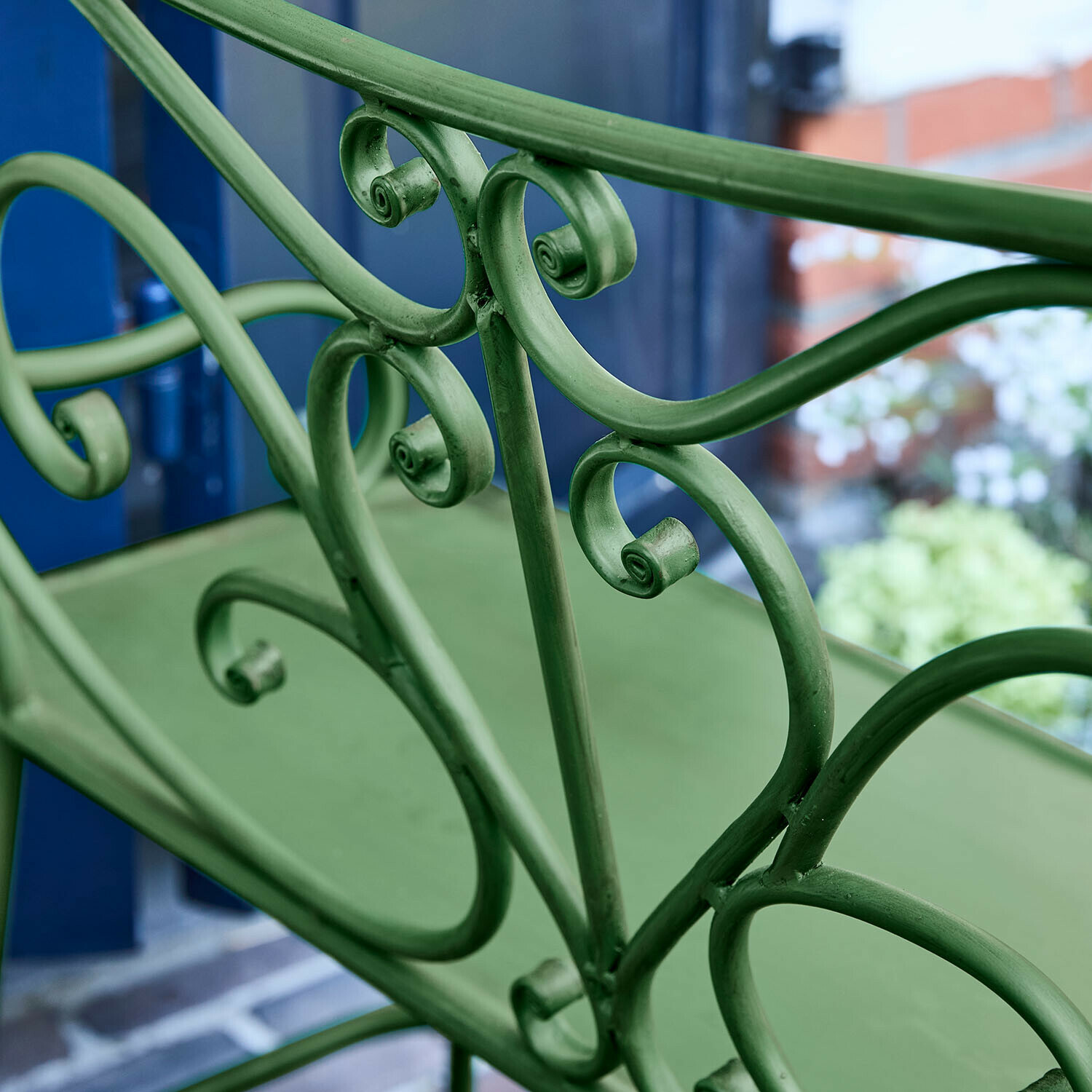 Grüner Metall-Gartenstuhl mit dekorativen Schnörkeln und bequemem Sitz
