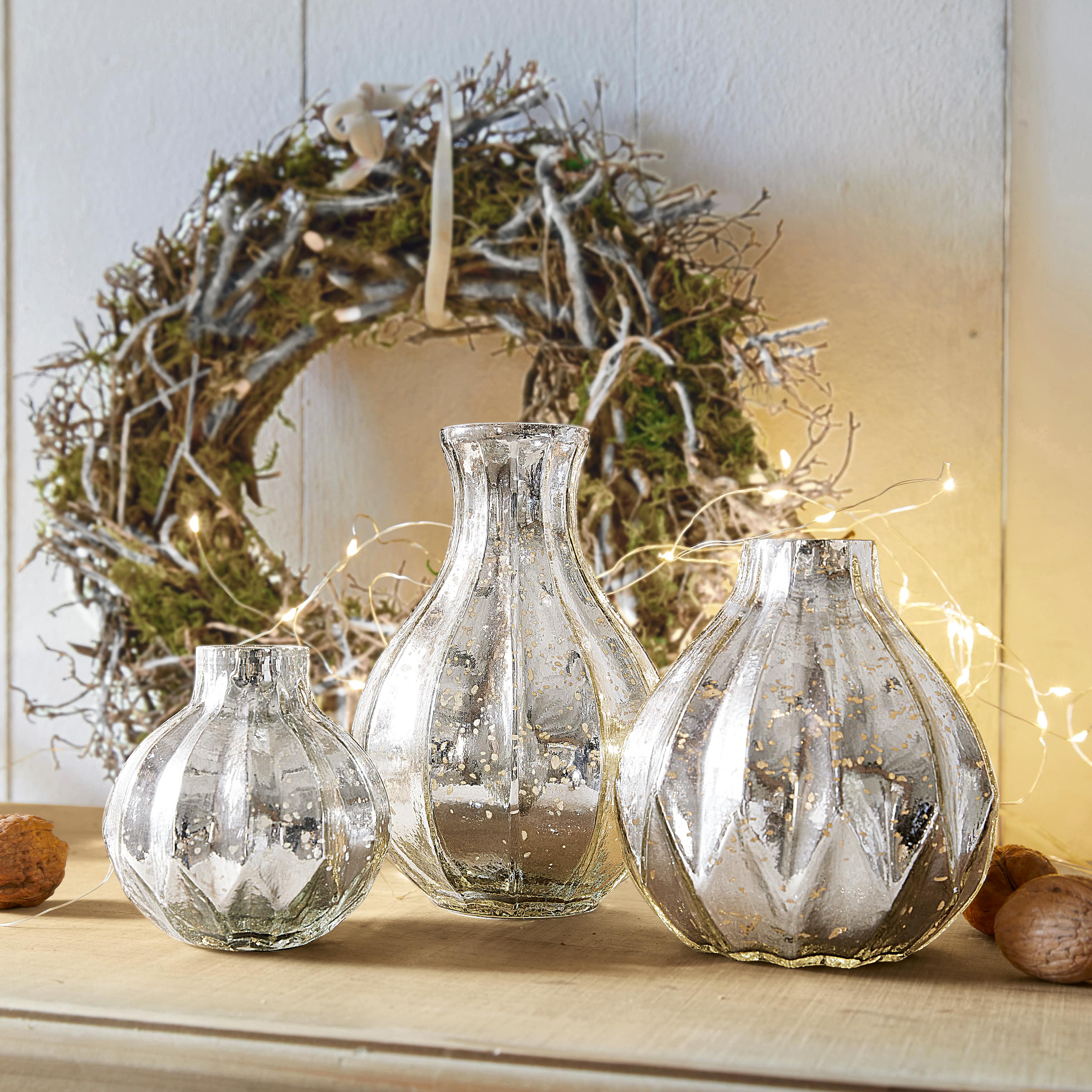 Set aus drei dekorativen Vasen aus silbernem Glas mit antikem Finish auf einem Holztisch
