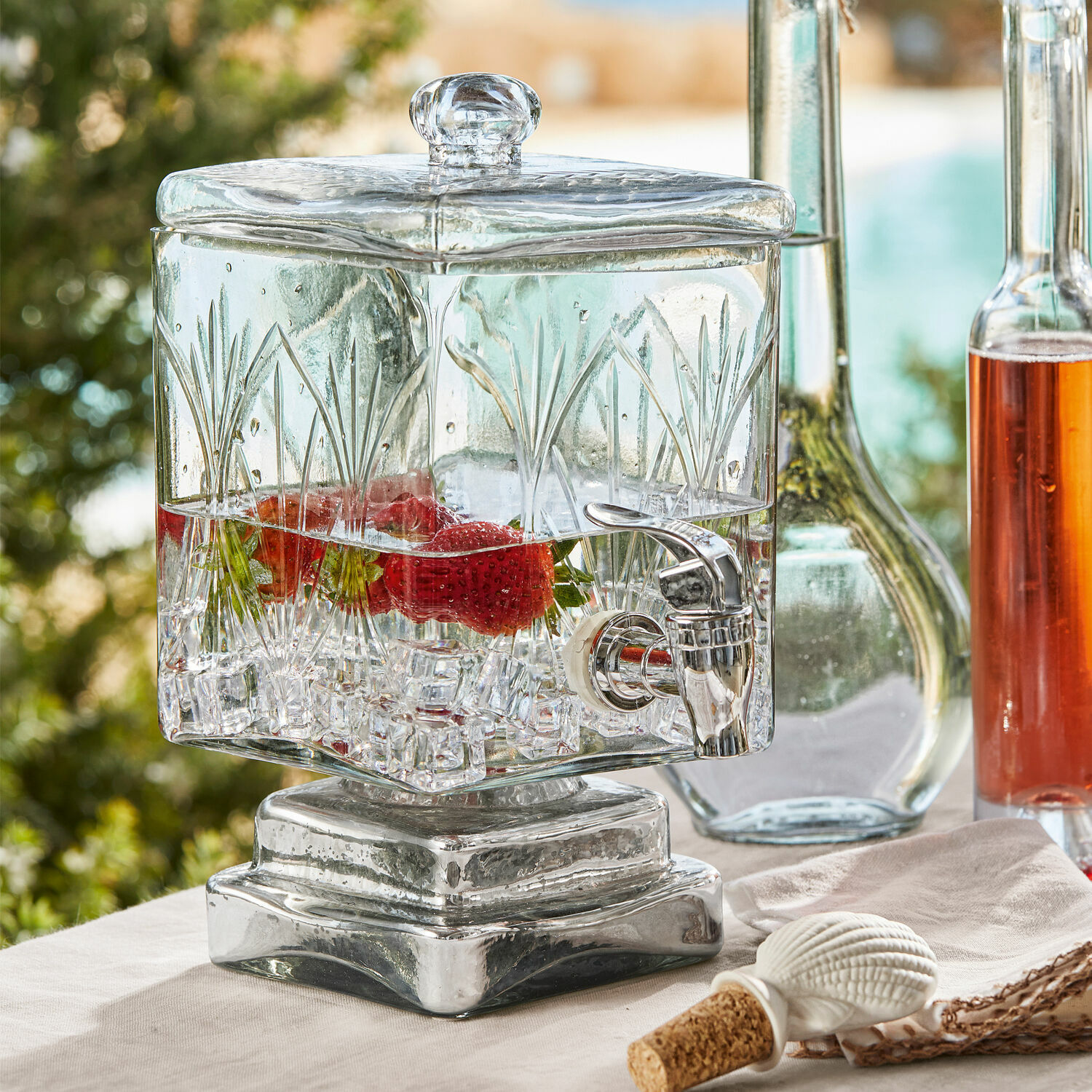 Glas-Getränkespender mit Deckel und Zapfhahn, mit Grasmuster verziert, gefüllt mit Erdbeeren