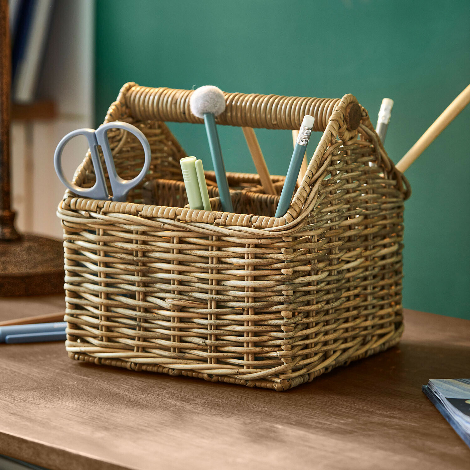 Natürlicher Rattankorb mit Fächern für Schere und Schreibutensilien auf Holztisch