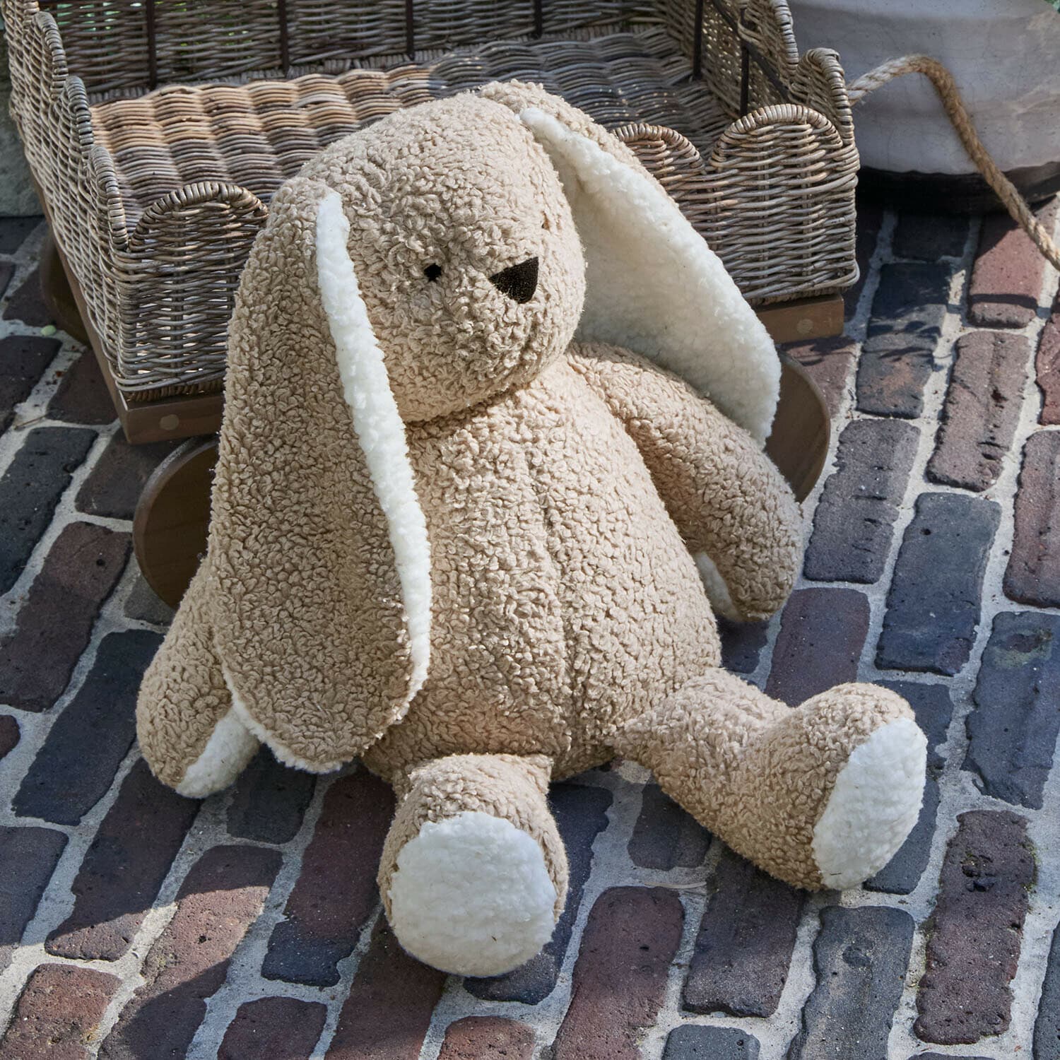 Stofftier Fluffernap Weicher Plüschhase in Beige mit weißen Ohren und Pfoten auf gepflastertem Boden