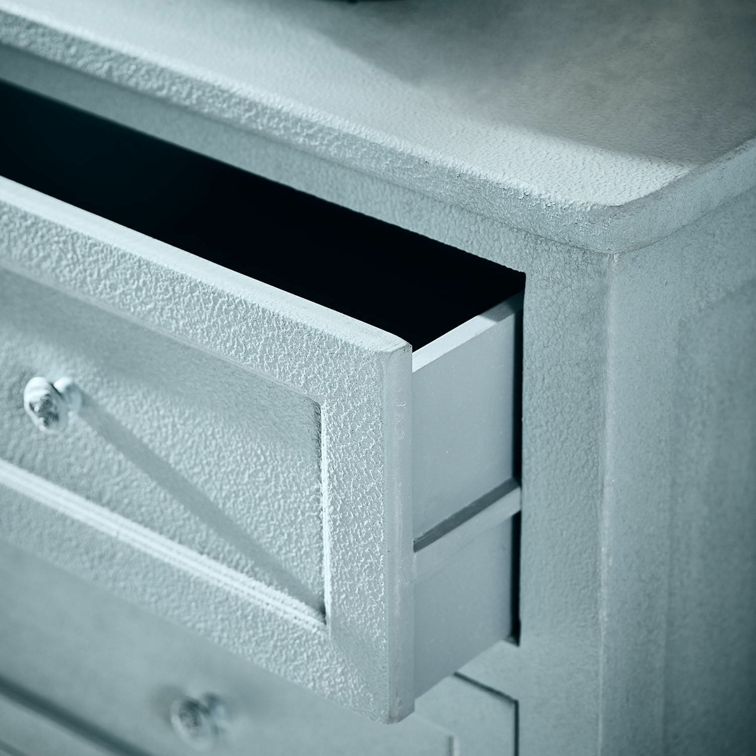 Grauer Schrank aus strukturiertem Material mit geöffneter Schublade und Metallgriffen