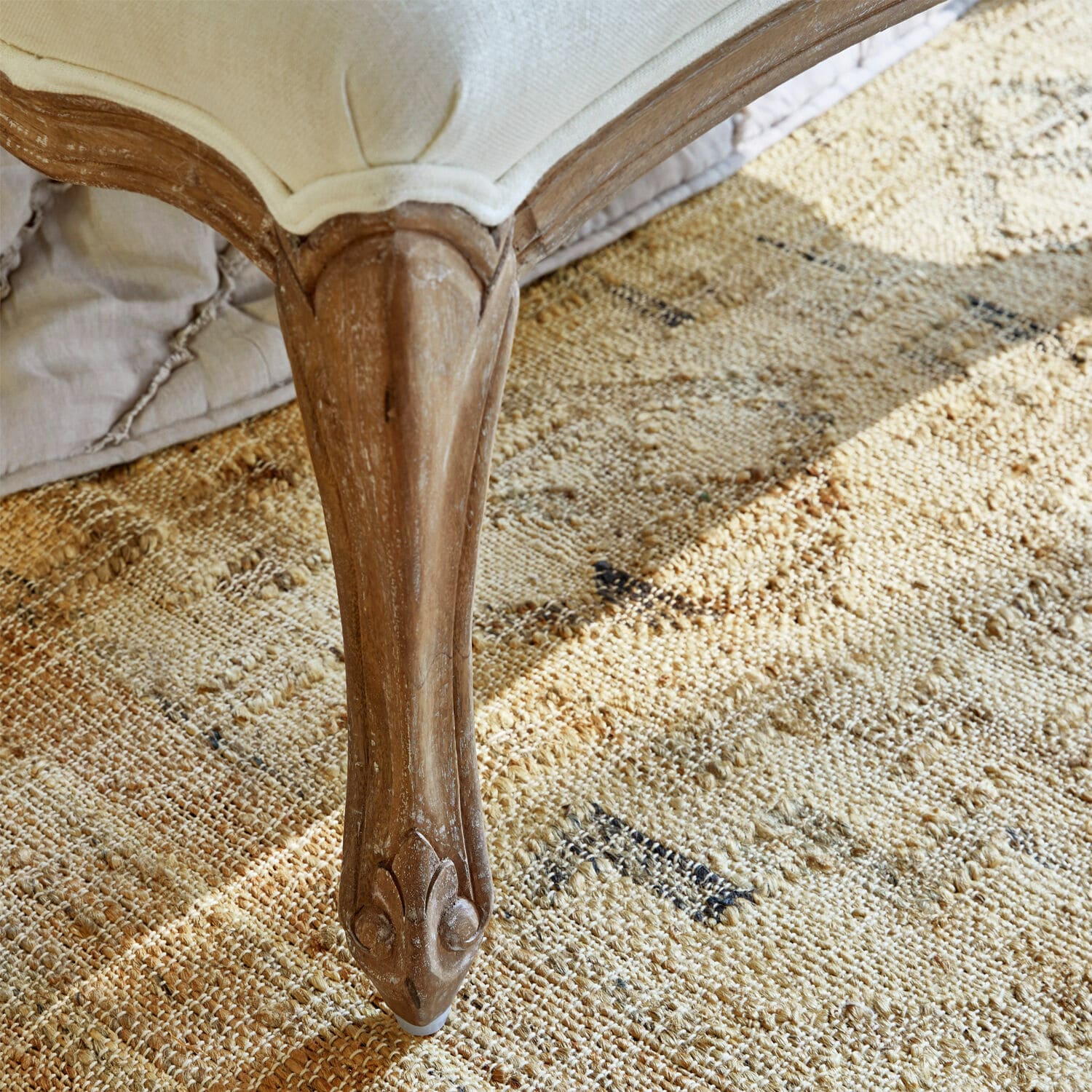 Holz-Möbelfuß in Naturfarbe auf beigem gemustertem Teppich, eleganter Vintage-Stil