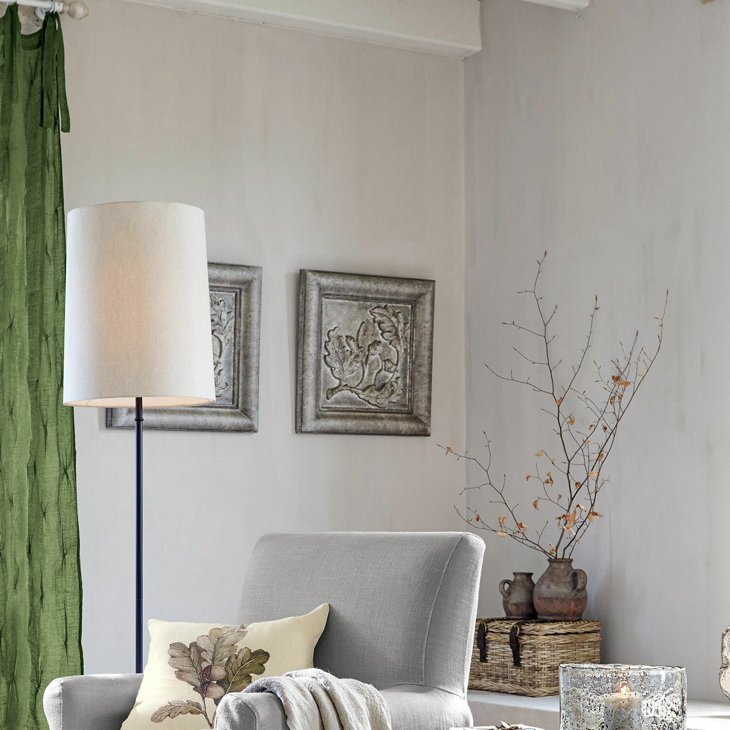 Grau gepolsterter Sessel mit Blattmuster-Kissen und Stehlampe in gemütlichem Wohnzimmer