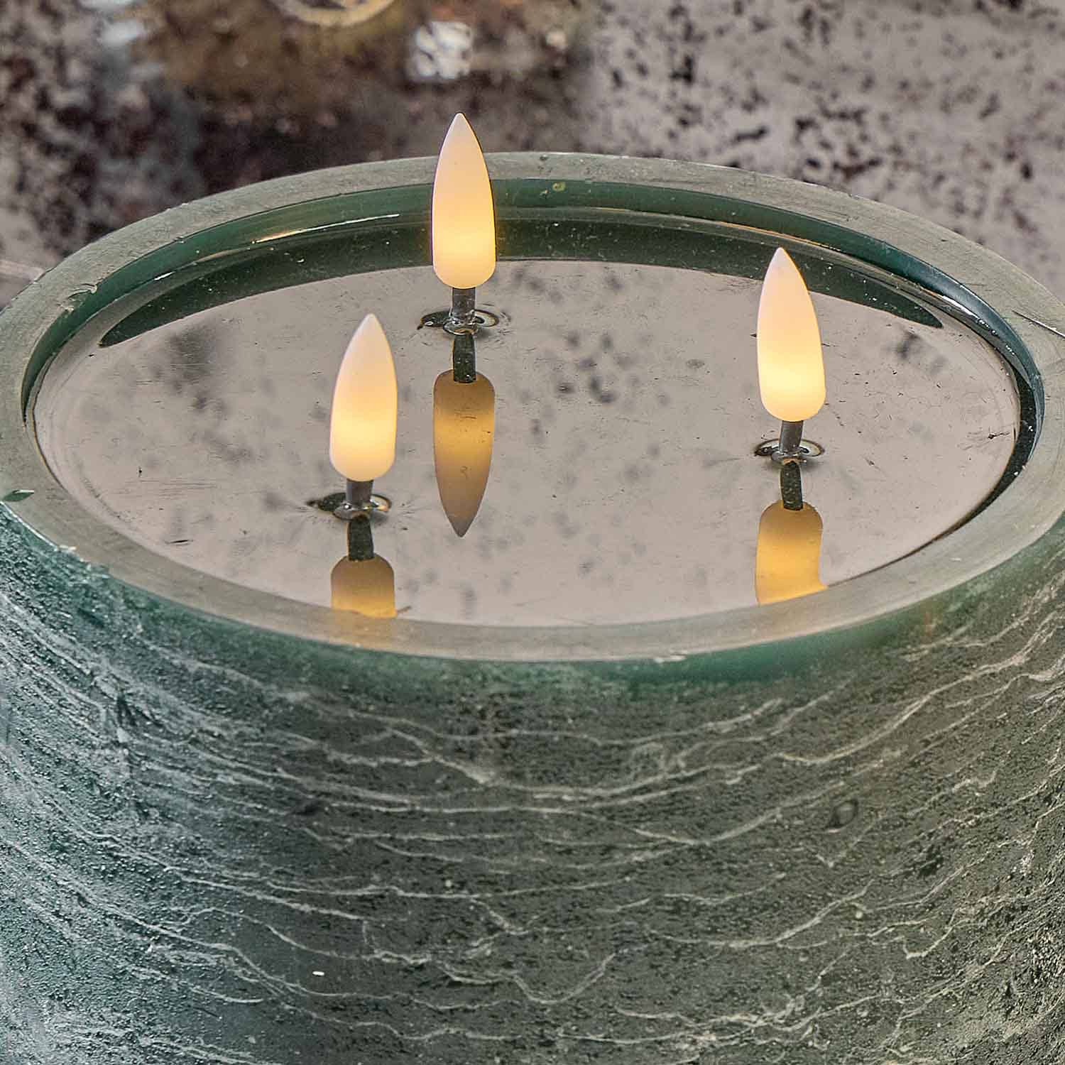 Grüner dekorativer Brunnen mit drei gelben LED-Flammenlichtern auf der Wasseroberfläche