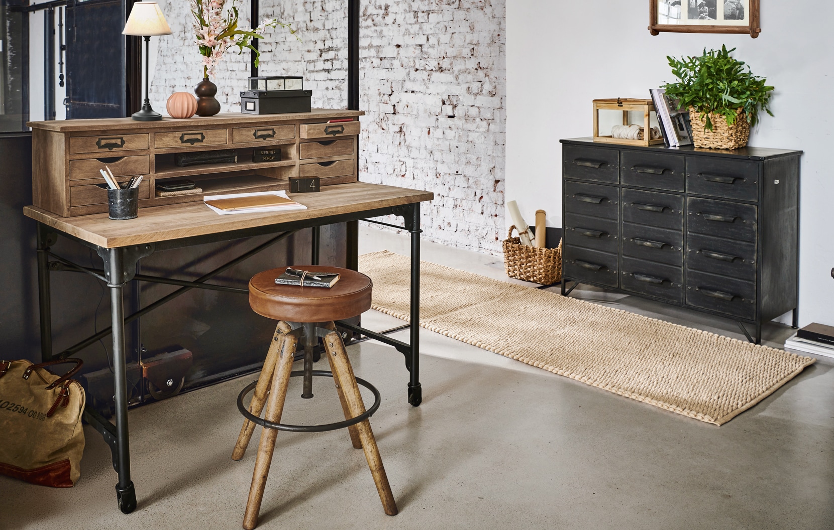 Industrieller Schreibtisch aus Holz und Metall mit vielen Schubladen und vintage Lederhocker im Raum