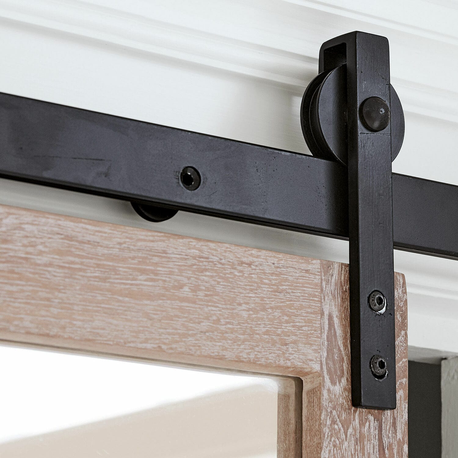 Schwarze Metall-Schiebetürhalterung an hellem Holz mit sichtbarem Laufradmechanismus