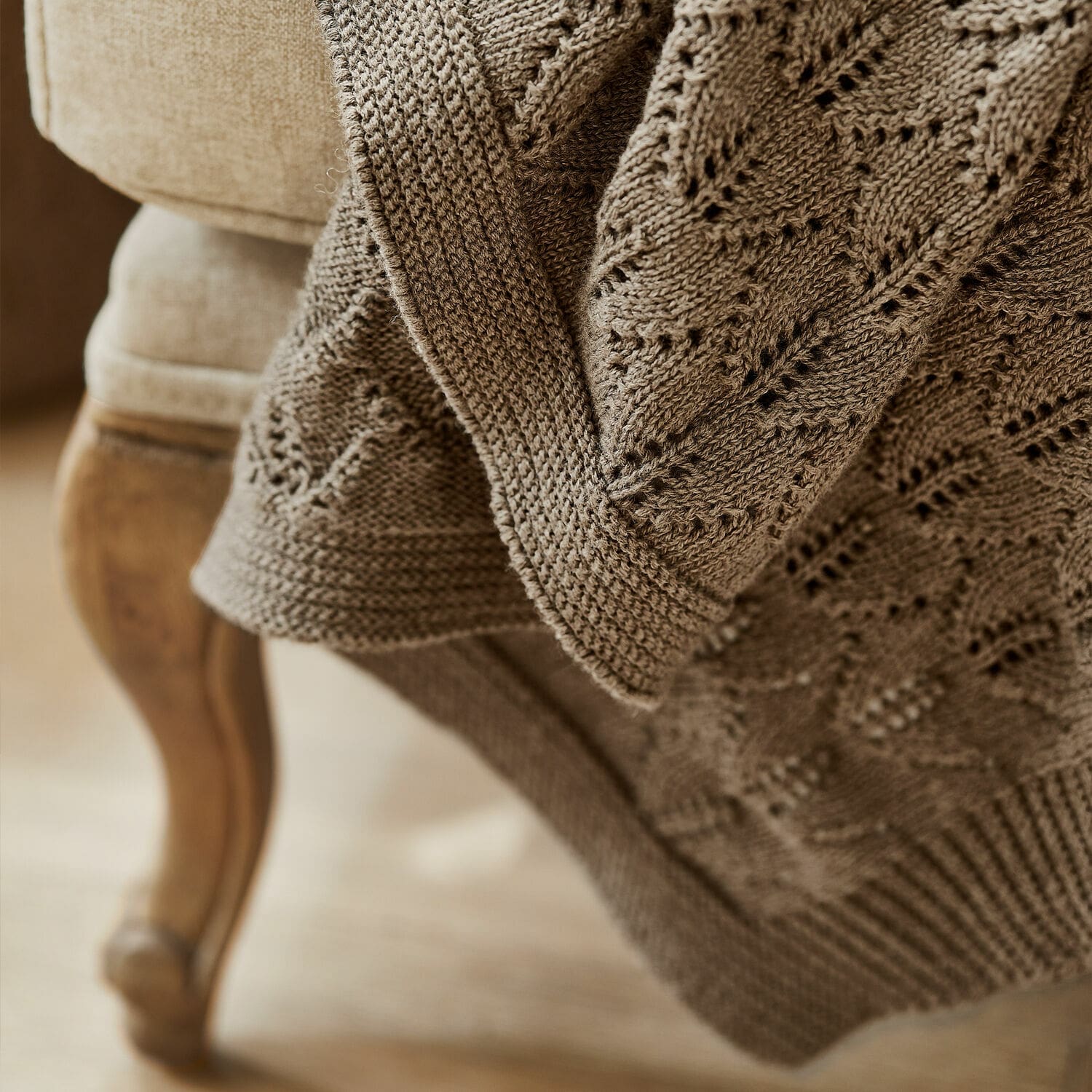 Braune gestrickte Decke mit Blattmuster auf Sessel, weiches Material für Wohnraumdeko