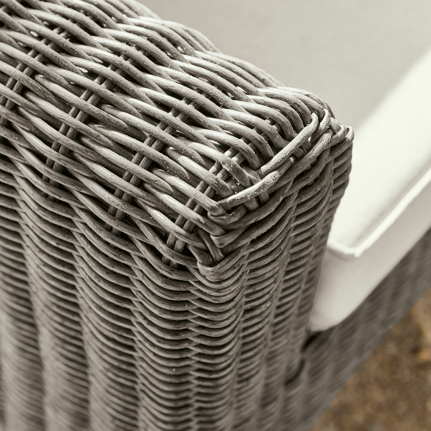 Nahaufnahme eines grauen Rattanmöbels mit hellem Polster für Wohnzimmer und Garten