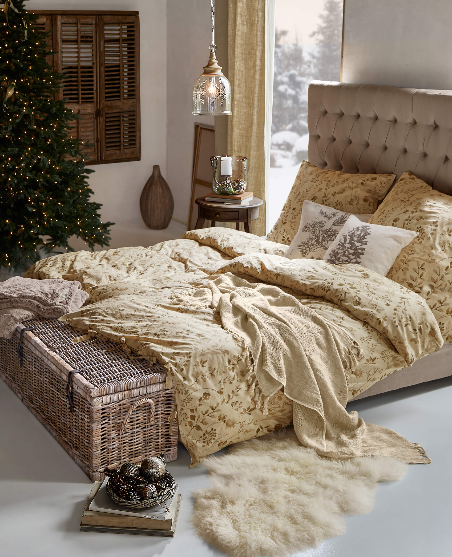 Gemütliches Schlafzimmer mit beiger Bettwäsche im Blumenmuster und weicher Decke auf dem Bett