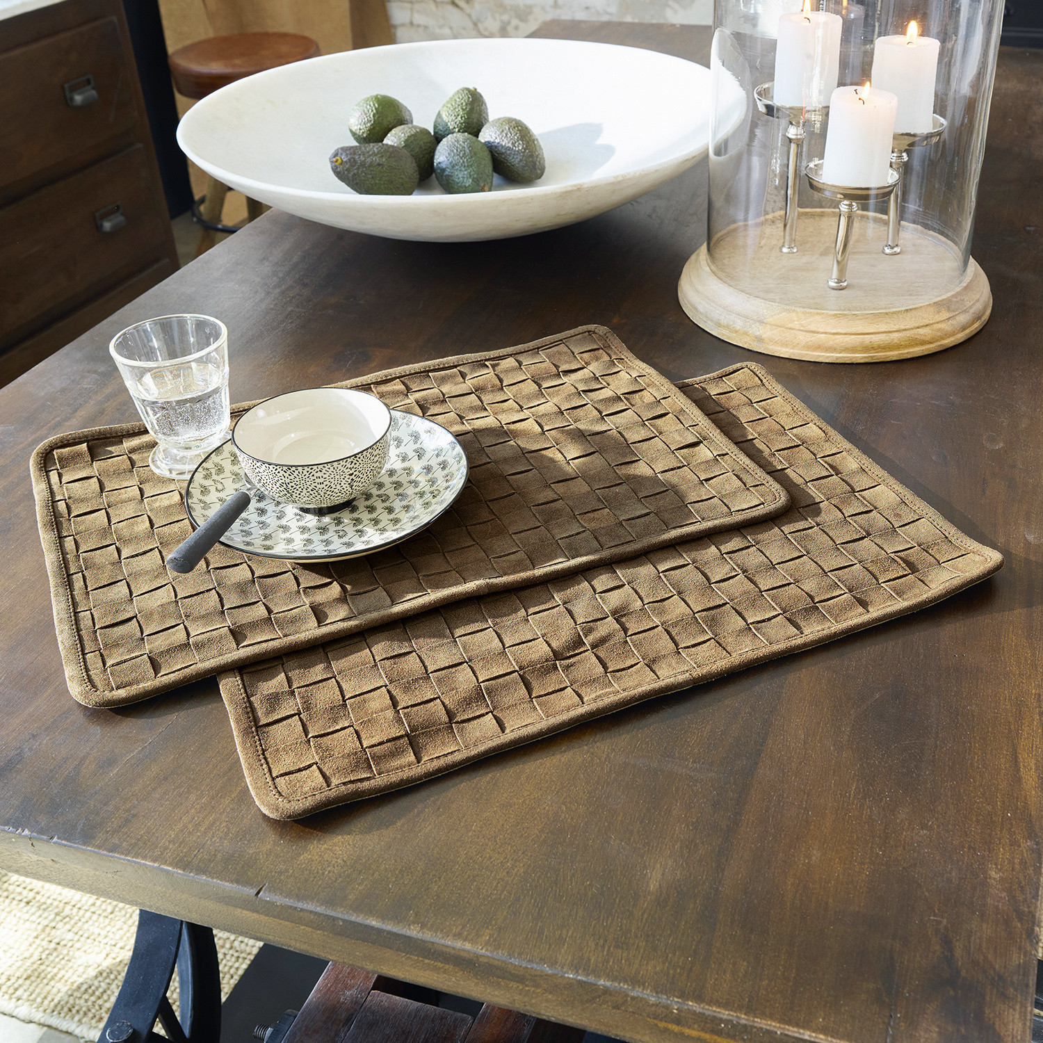 Braune Tischsets aus gewebtem Stoff auf Holztisch mit Geschirr und Kerzenhalter