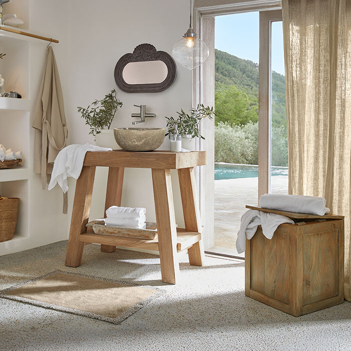 Badezimmer mit Holzwaschtisch und steinerner Schale, natürliche Farben und Pflanzen