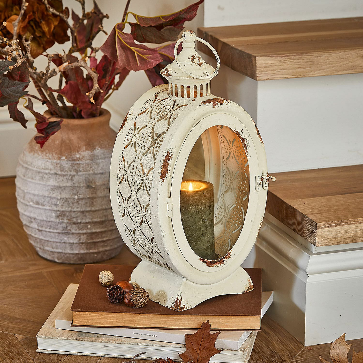 Laterne Sublimelle Vintage Metalllaterne in Creme mit brennender Kerze und herbstlicher Dekoration auf Büchern