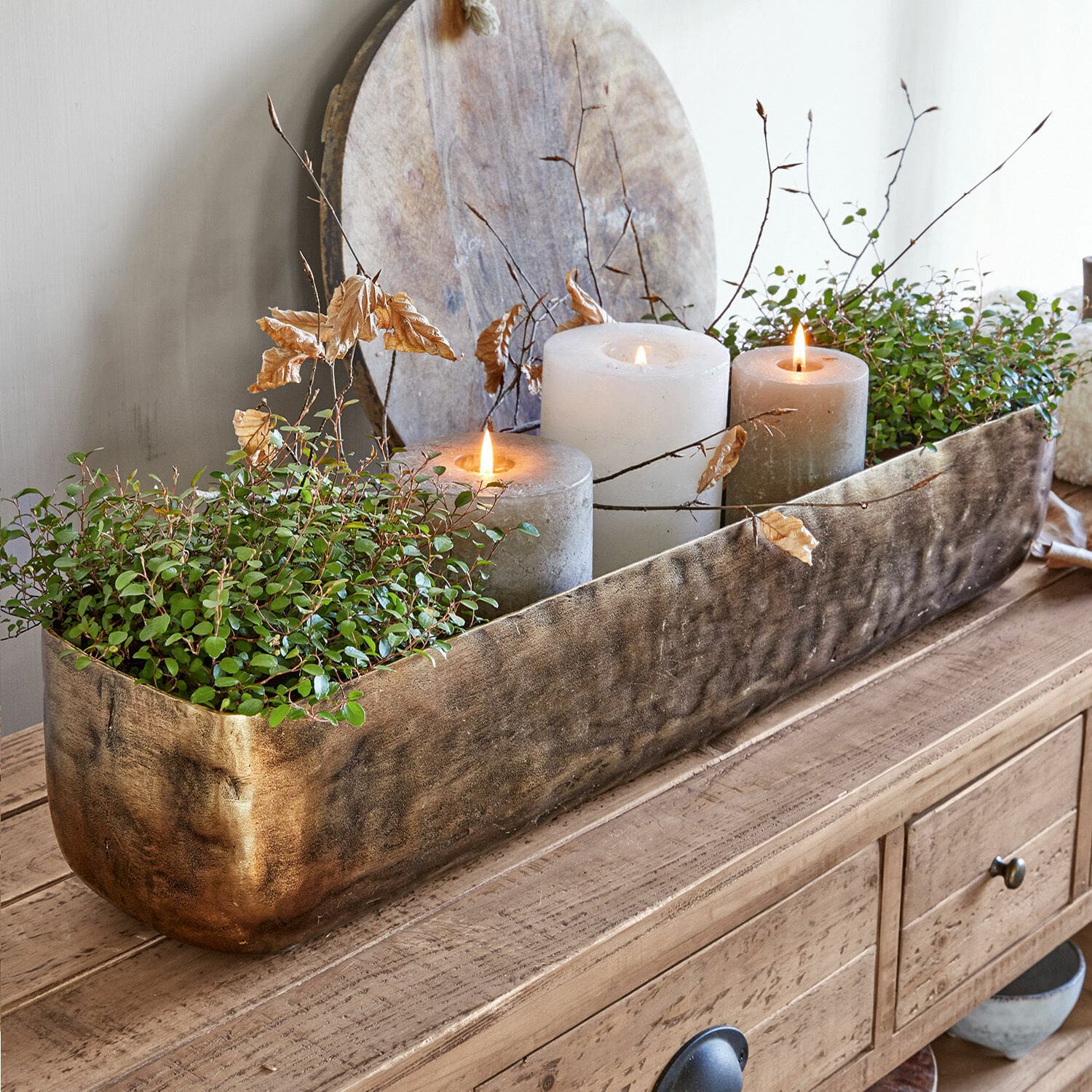 Schale Skye Dekorativer goldener Metall-Blumenkasten mit grünen Pflanzen und drei Kerzen auf Holztisch