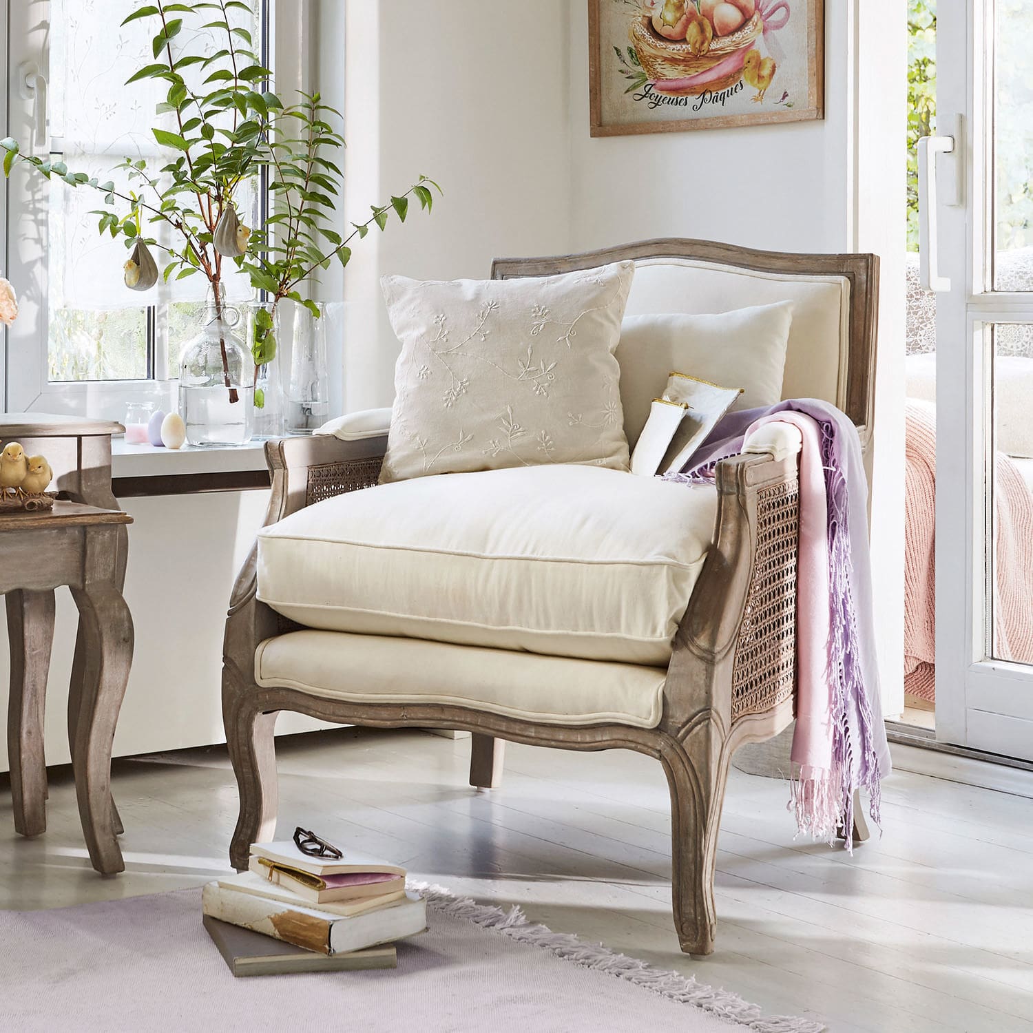 Eleganter Holzsessel mit hellen Polstern und pastellfarbenem Plaid in hellem Raum