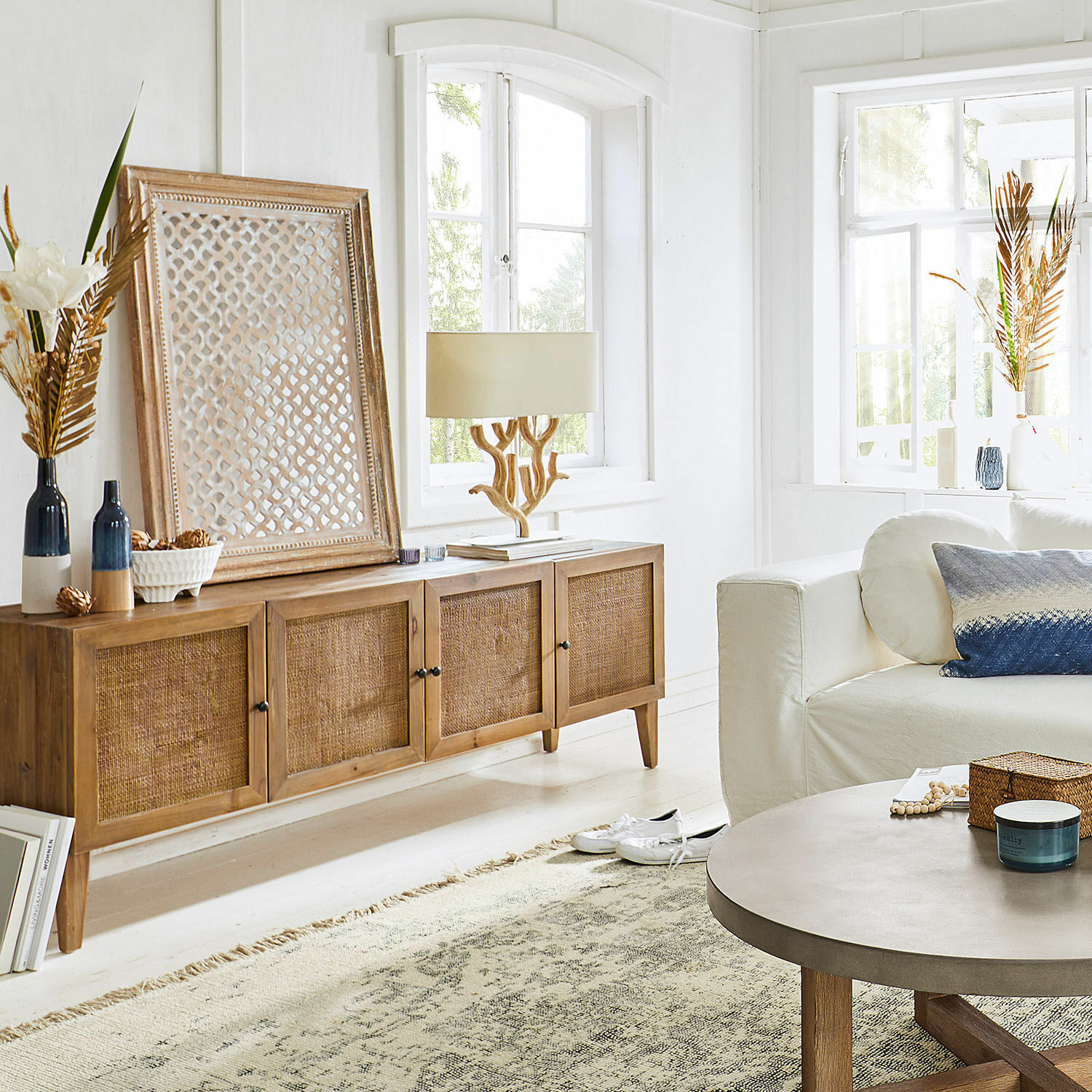 Holzkommode mit geflochtenen Fronten in Naturfarbe in hellem Wohnzimmer mit Dekorationen