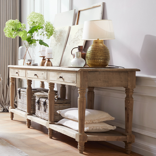 Konsolentisch aus hellem Holz mit Dekoration und Lampe auf hellem Boden in stilvollem Raum