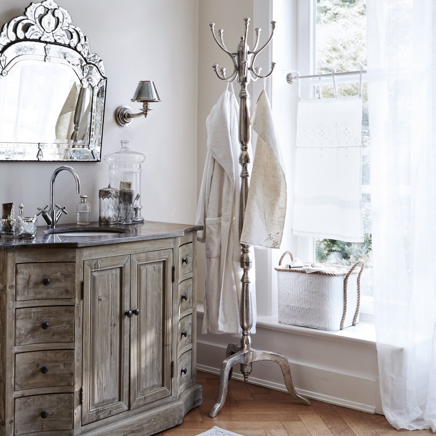 Elegantes Badezimmer mit Holzschrank, Metallgarderobe und dekorativem Spiegel in hellen Farben