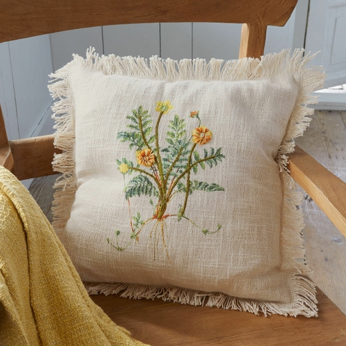 Beige Leinenkissen mit Fransen und besticktem Blumenmotiv auf Holzstuhl