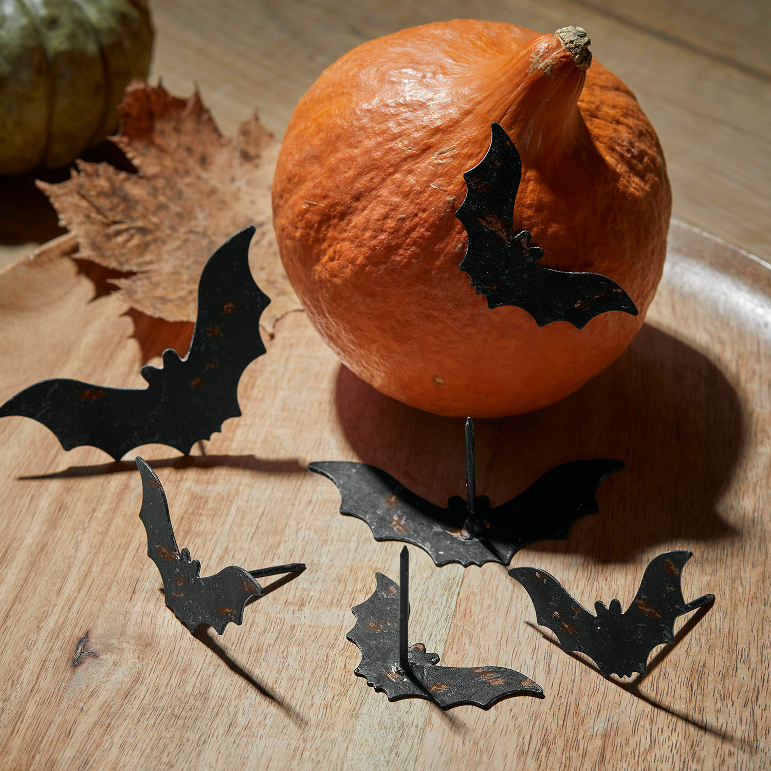 Schwarze Metall-Nachtfalter-Dekorationen auf Holz mit orangefarbener Kürbis-Halloween-Deko