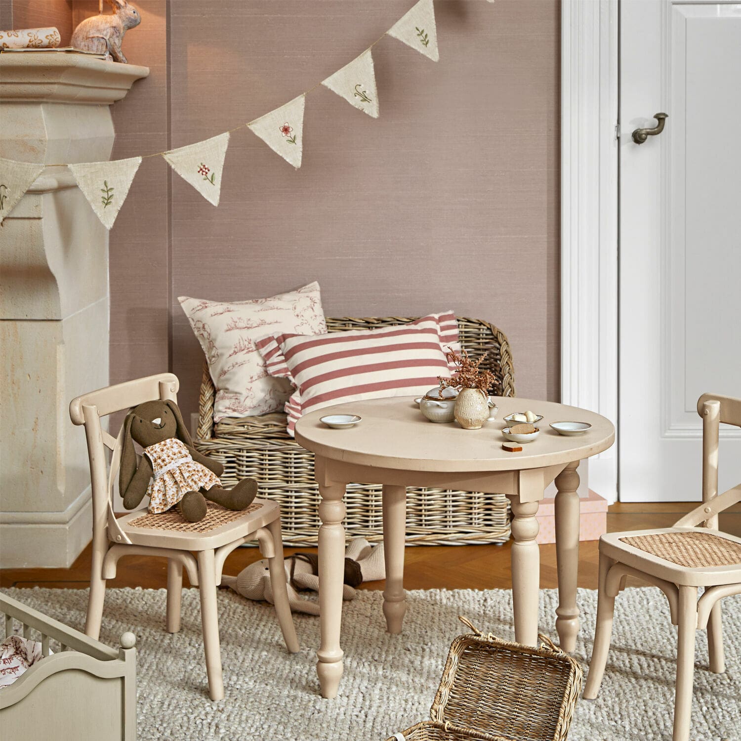 Beiger Holztisch und Stühle mit Rattansitz im Kinderzimmer mit Spielzeug und Kissen