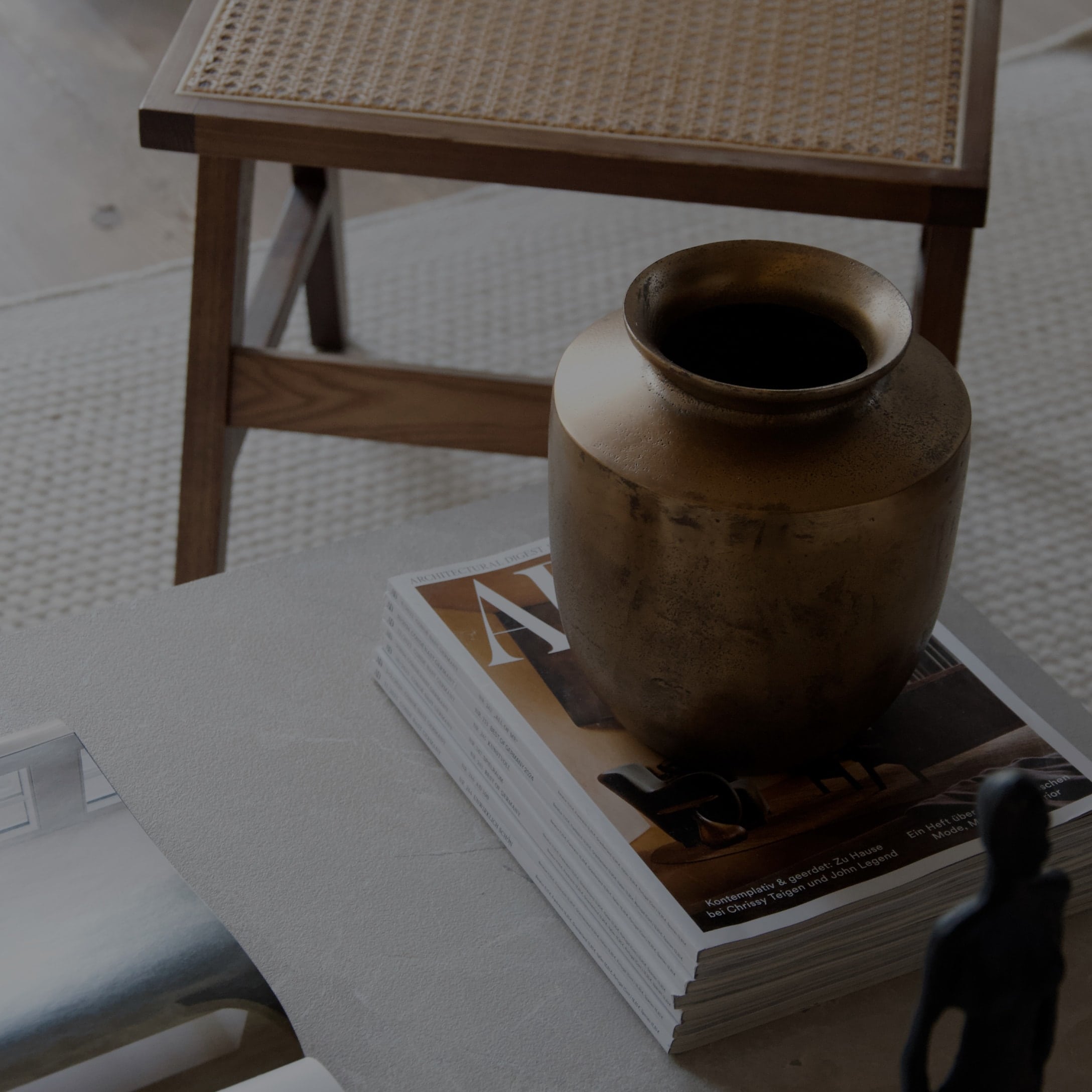Dekorativer Messingvase auf einem Stapel Magazine auf hellem Tisch in modernem Interieur
