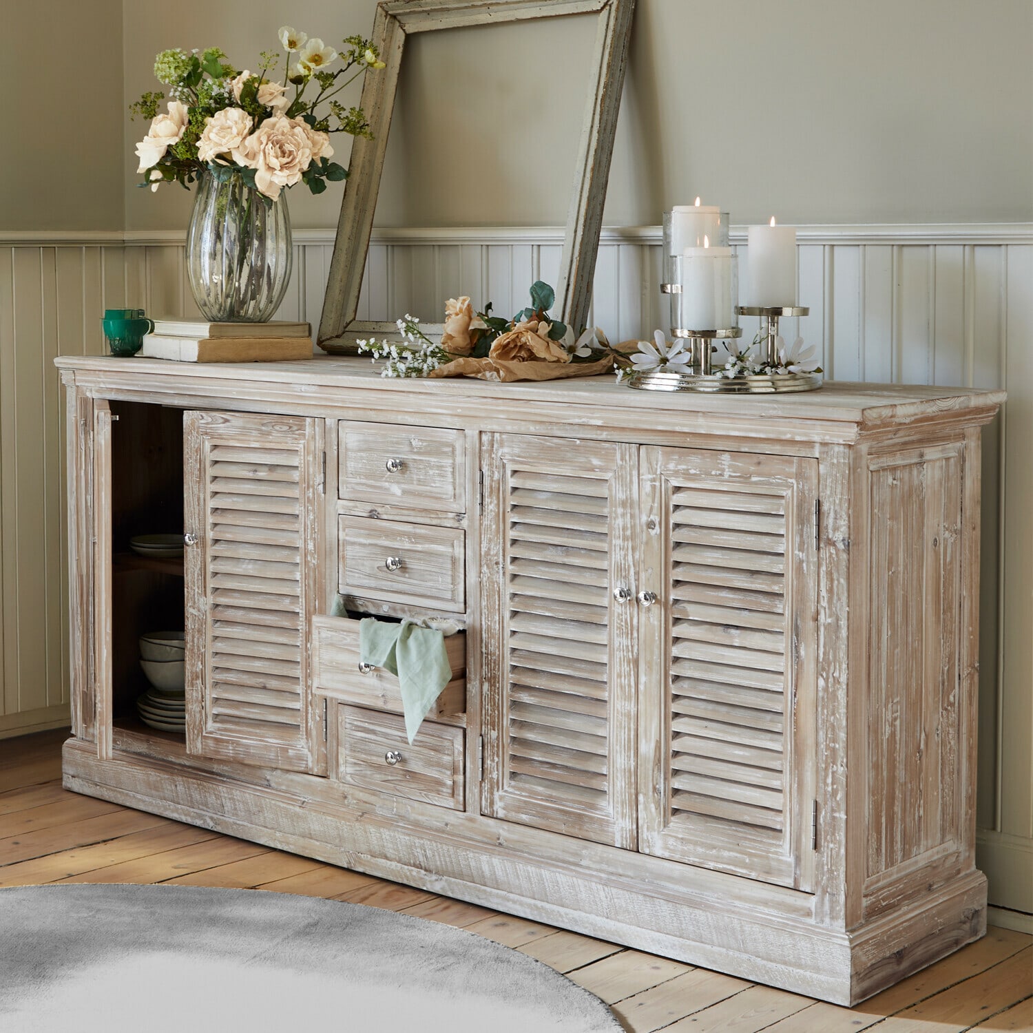 Rustikales Sideboard aus Holz mit weiß gewischtem Finish, Dekorationen und Kerzen im Wohnzimmer