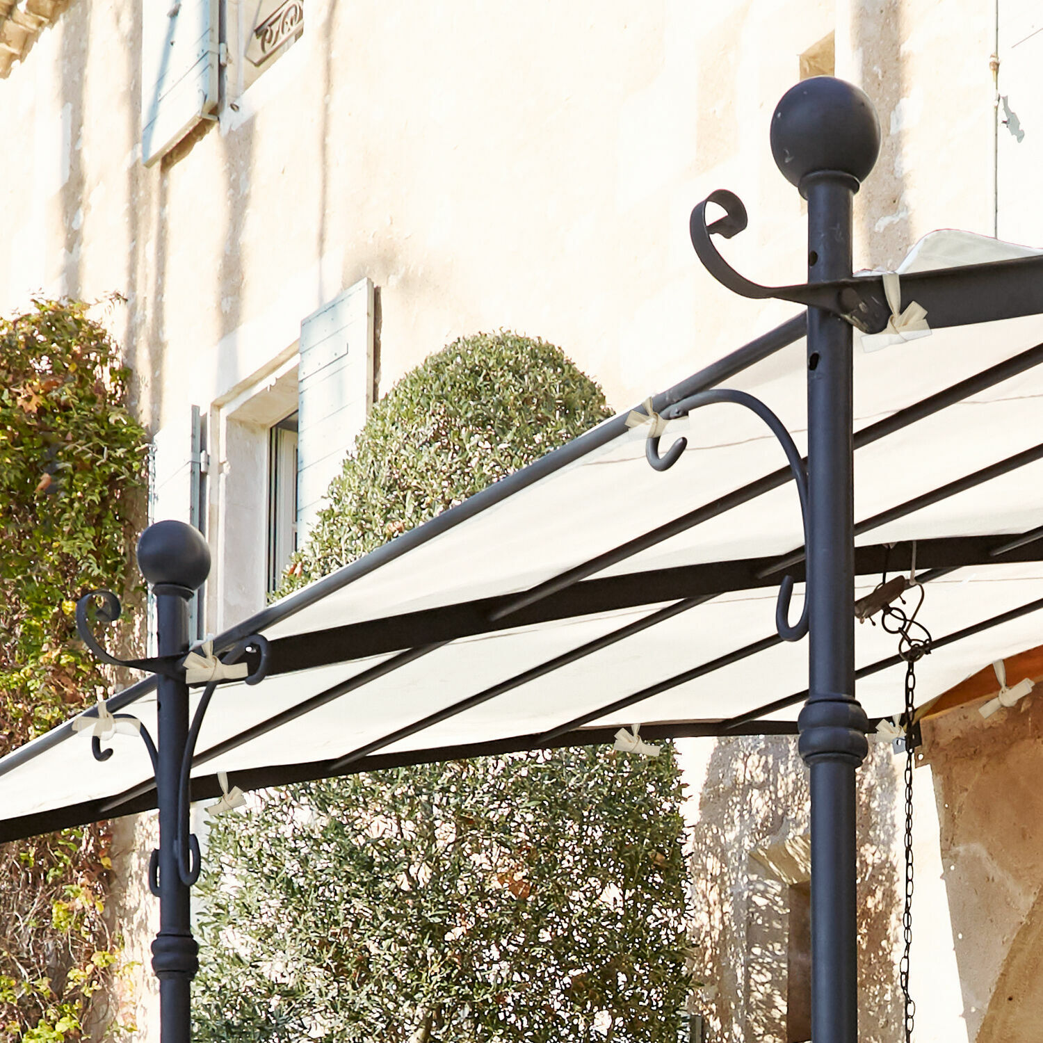 Schwarze Metallkonstruktion mit weißem Stoffdach auf Terrasse an Hauswand