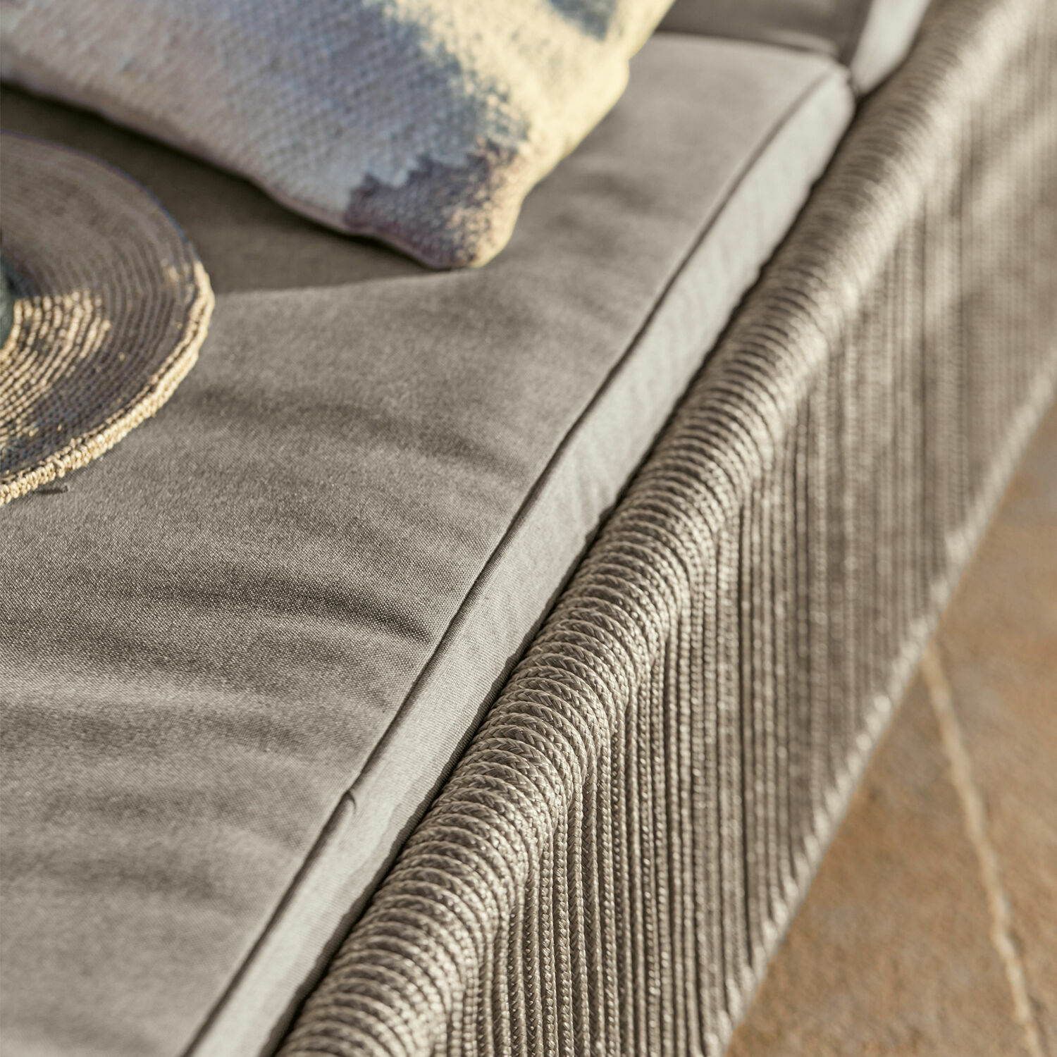 Graues Stoffsofa mit geflochtenem Armteil und dekorativem Kissen, gemütliches Wohnzimmermöbel