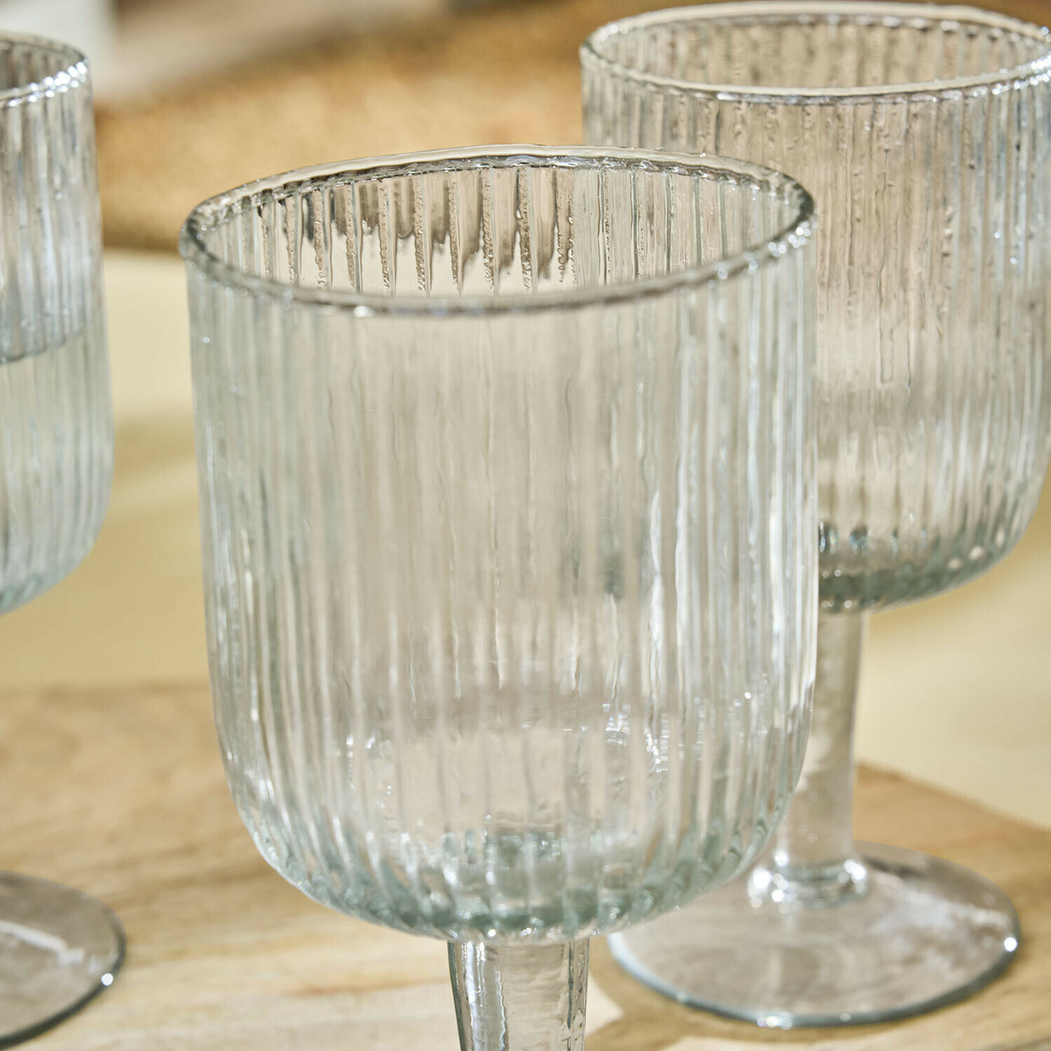 Transparente Weingläser aus geriffeltem Glas mit Stiel, ideal zum Servieren von Getränken.